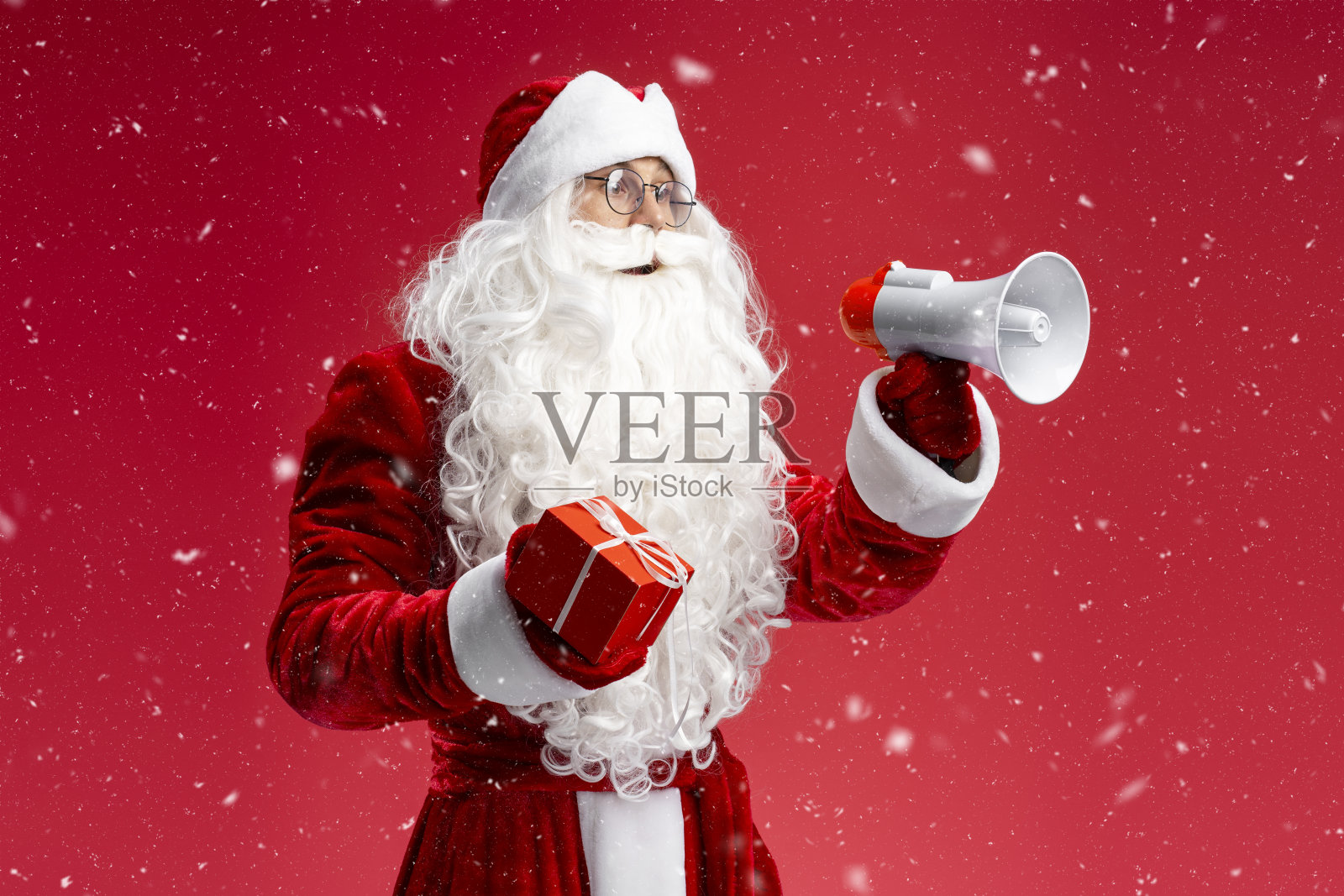 圣诞老人拿着礼盒和扬声器宣布冬季销售孤立在红色背景照片摄影图片