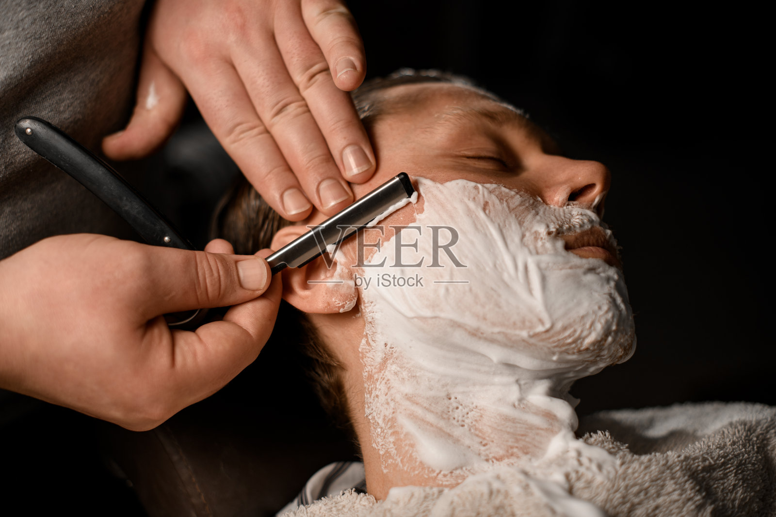 专业理发师剃须年轻有吸引力的客户与老式直刀与不锈钢在现代理发店照片摄影图片