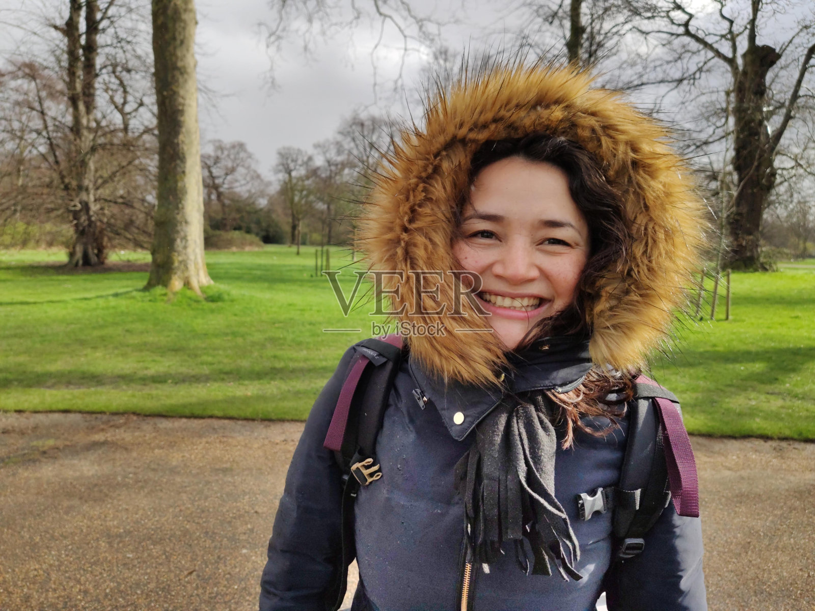 在伦敦的海德公园里，一位拉丁妇女面带微笑，穿着夹克和无边帽照片摄影图片