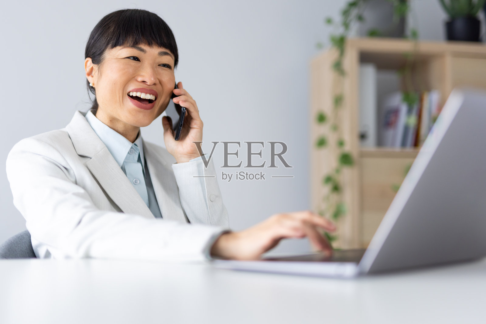 亚洲女性在办公室使用笔记本电脑和智能手机照片摄影图片