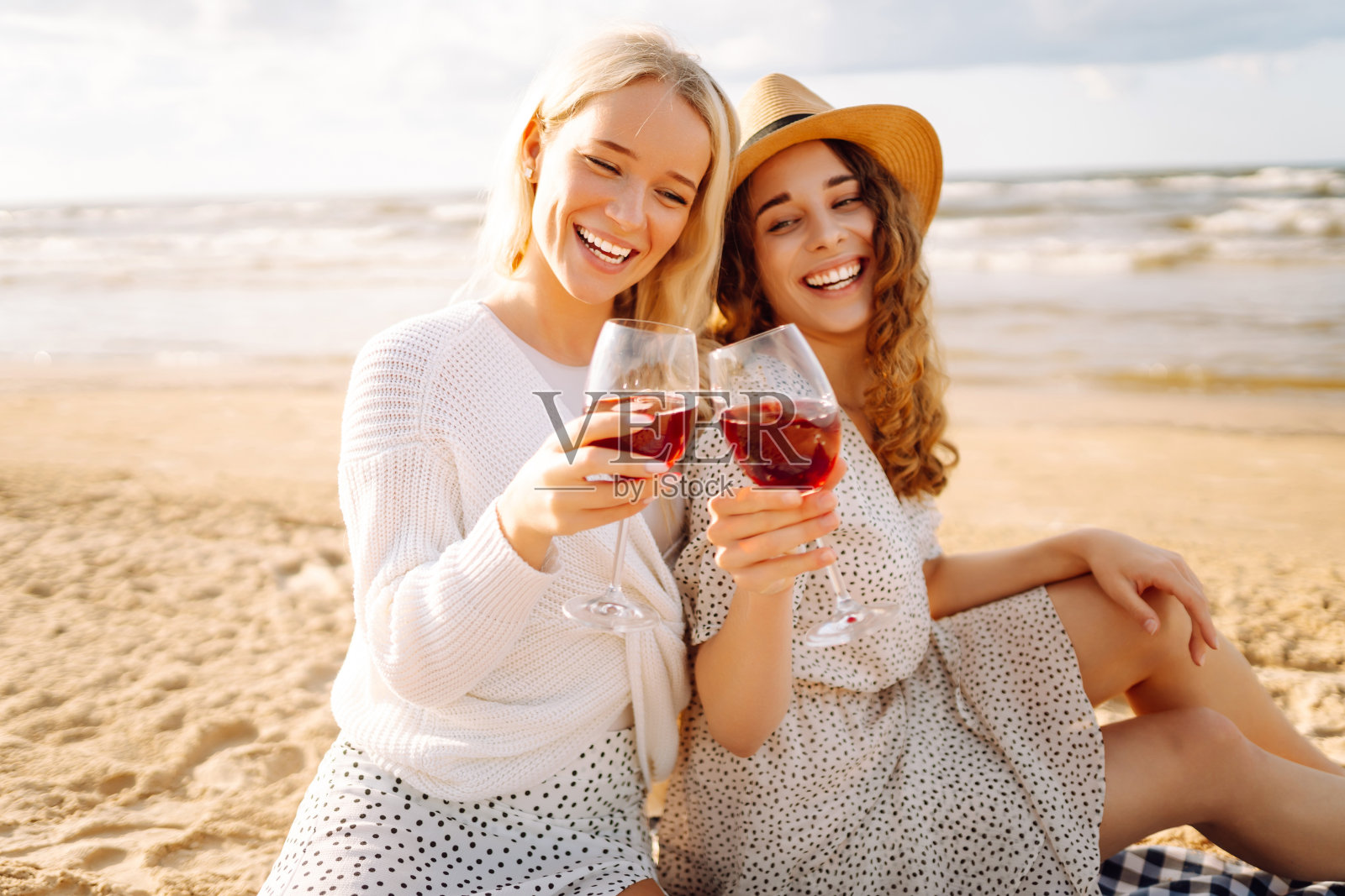 两个女性朋友在海边野餐，喝着酒，吃着早午餐。照片摄影图片
