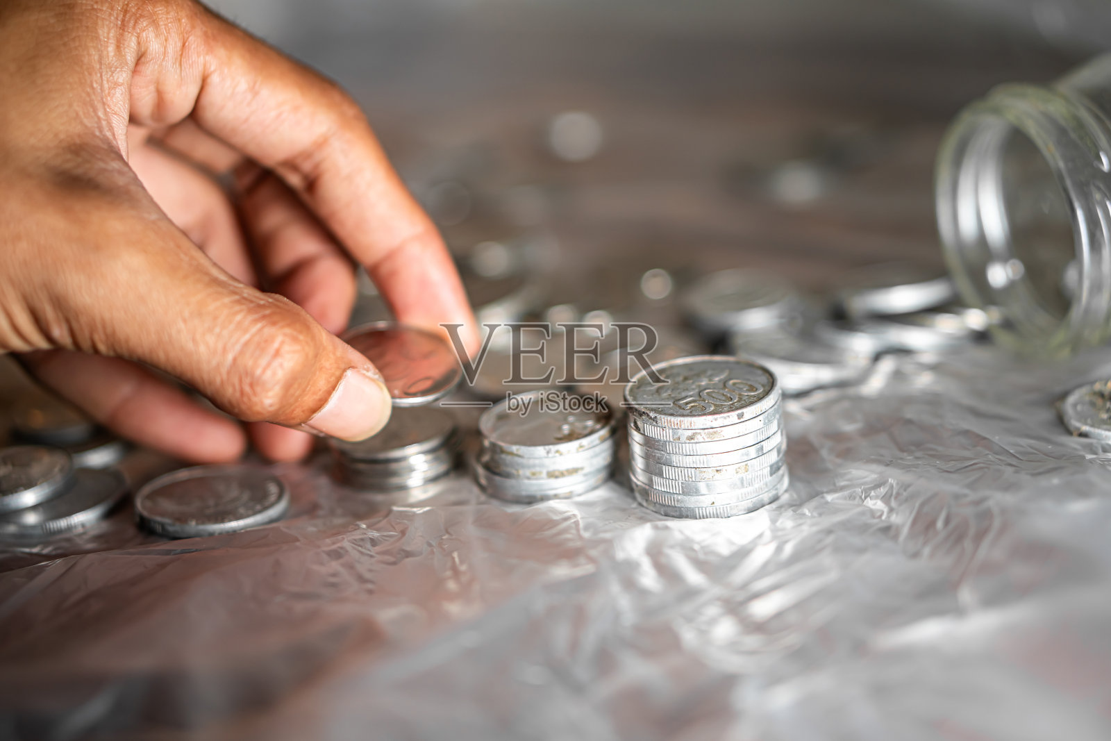 在透明的表面上用手堆叠银币照片摄影图片