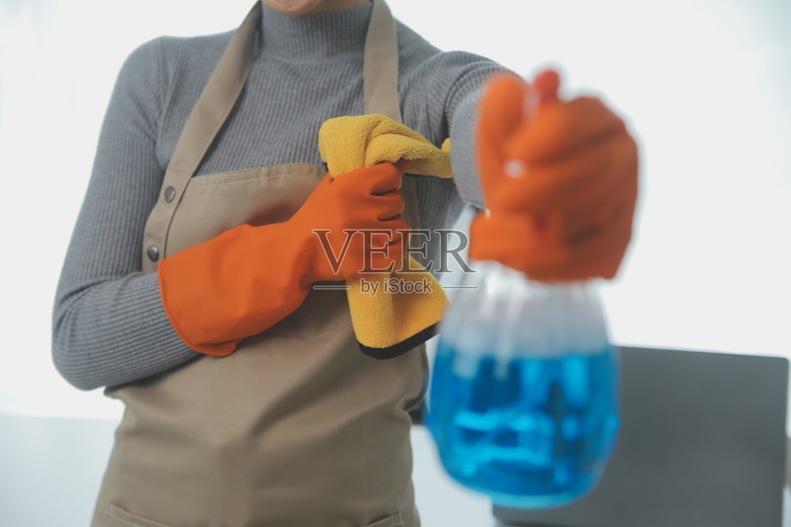 妇女在家里用抹布和扩散器清洁桌子。照片摄影图片