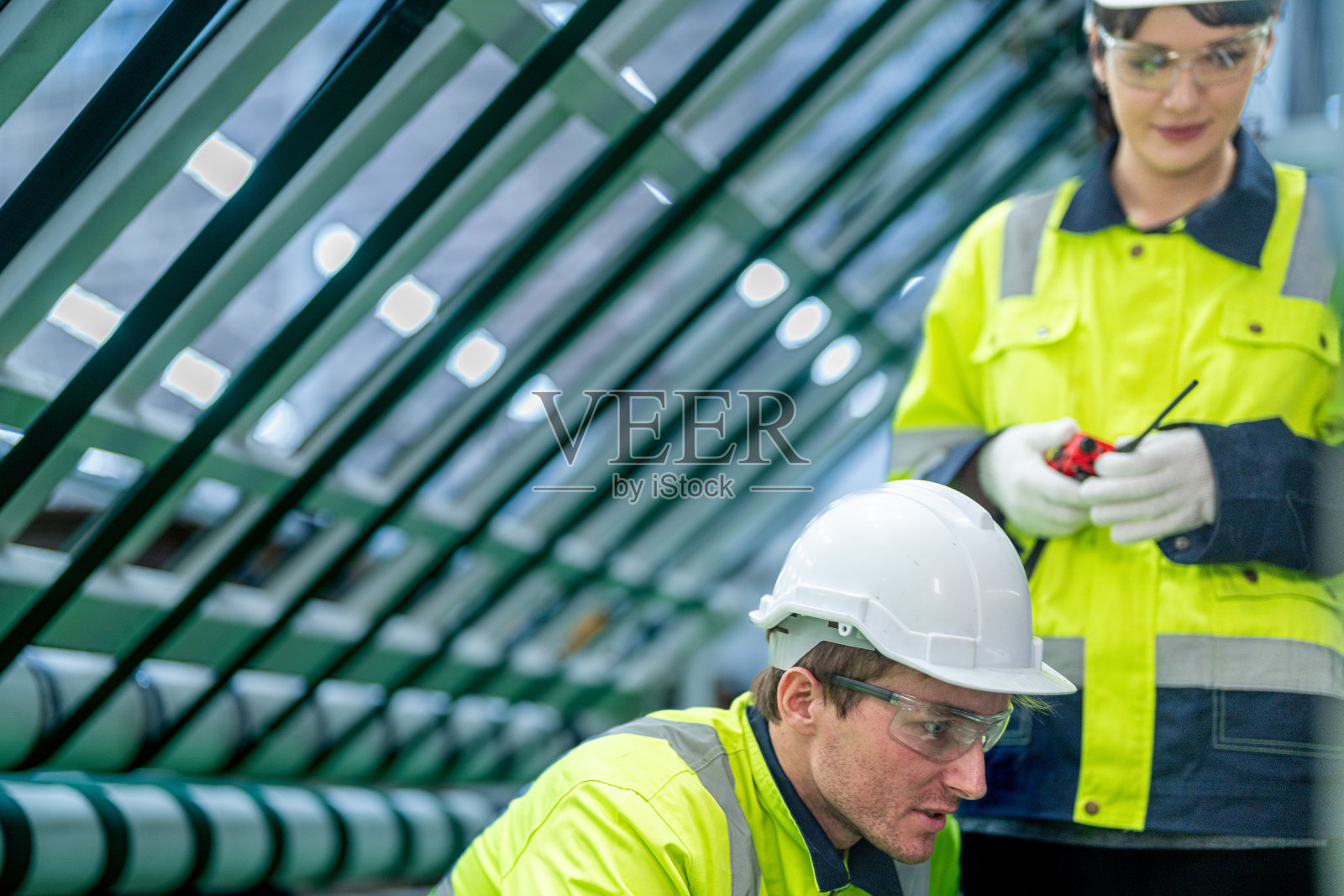 在一家生产工业技术产品的工厂里，穿着整洁工作服的男女工程师准备和控制大型现代机器的生产系统。照片摄影图片