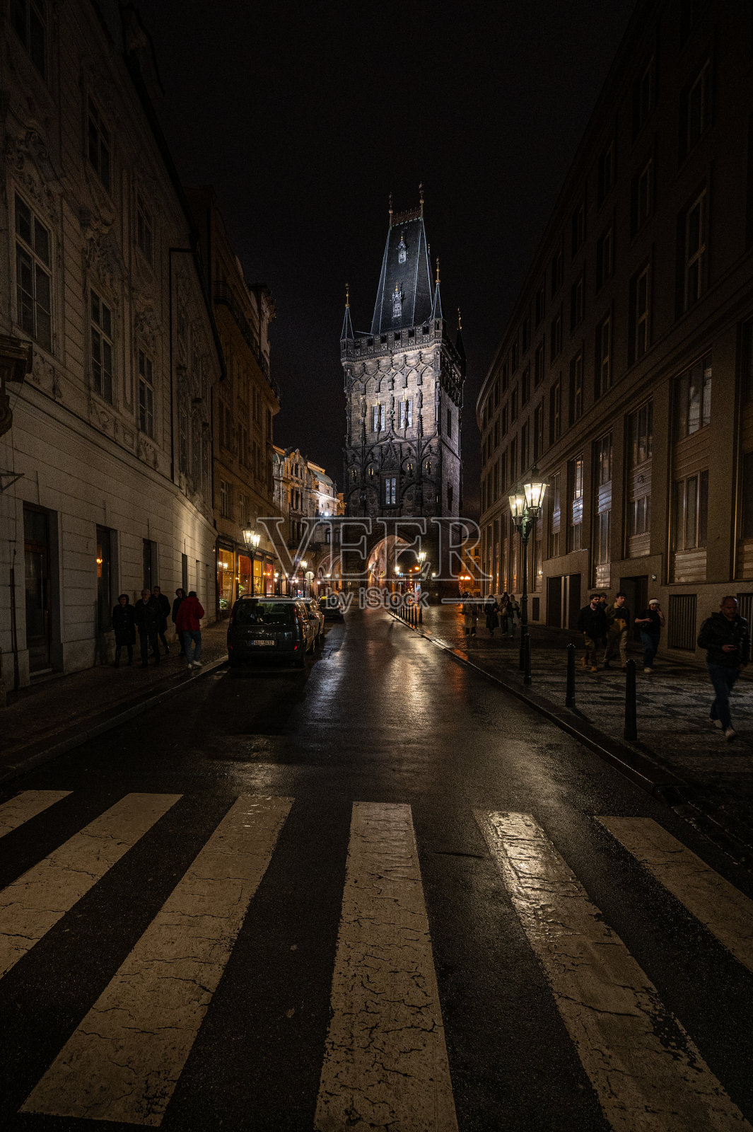 布拉格，夜晚的城市街道上，人们走在建筑物前的人行道上照片摄影图片