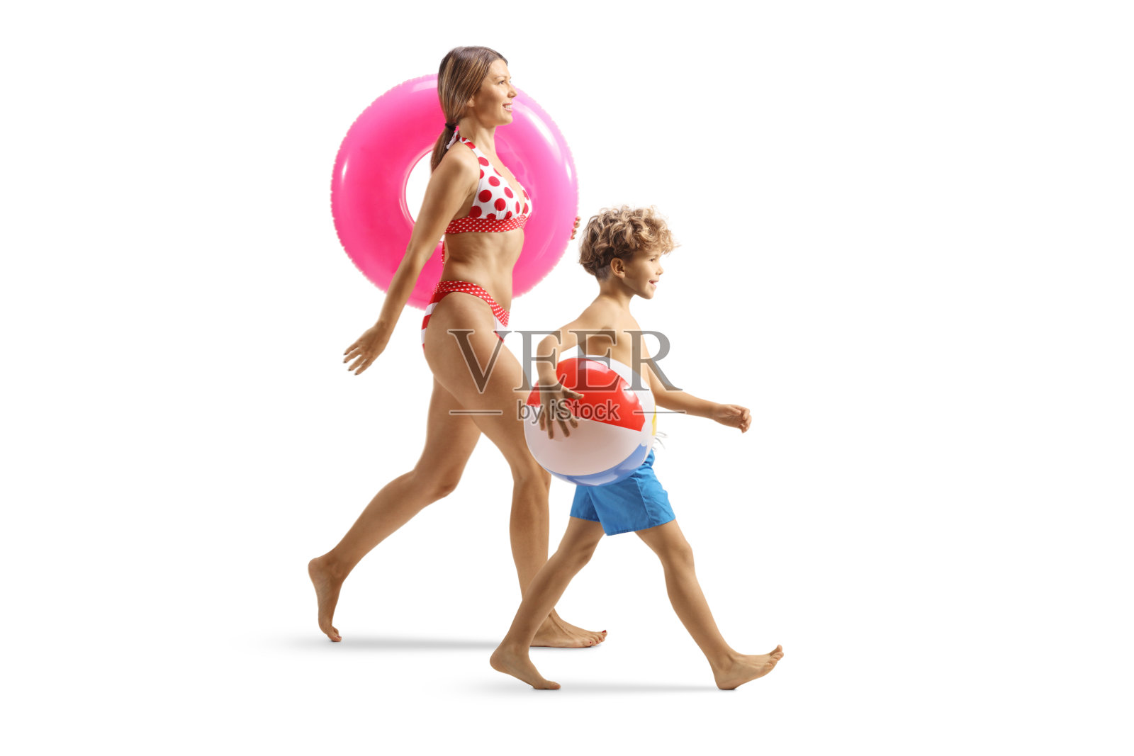 一名身穿比基尼的年轻女子手持游泳环，男孩手持沙滩球照片摄影图片