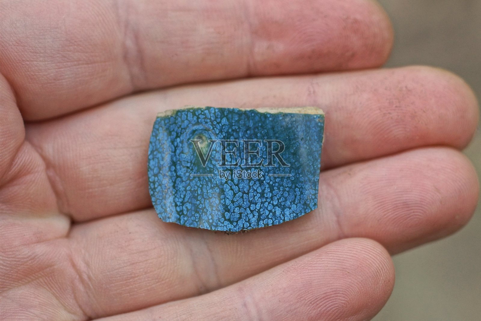 手里拿着一块蓝色的小旧瓷砖照片摄影图片