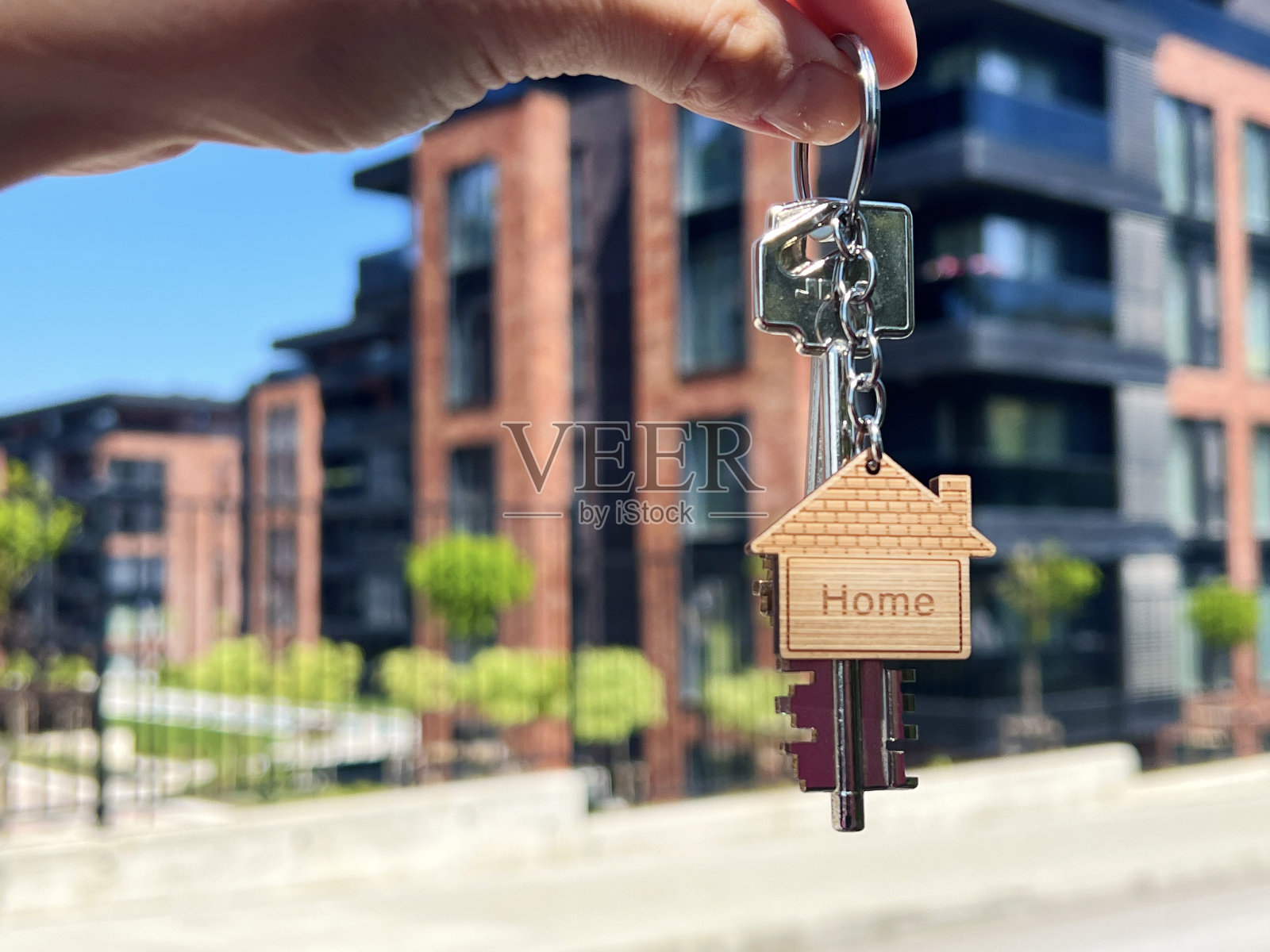 手持钥匙和钥匙链形状的房子。买房概念照片摄影图片