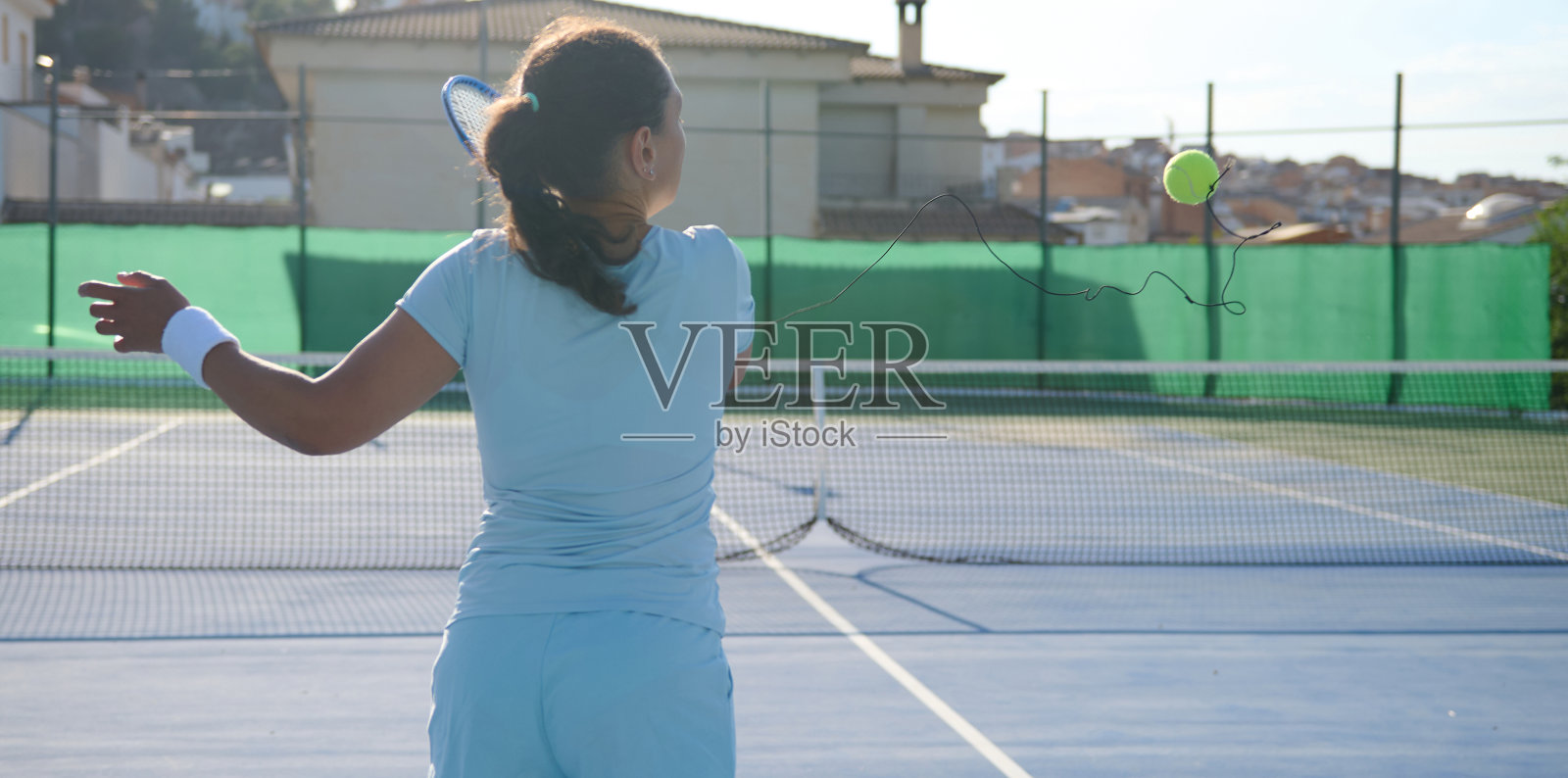 一名40多岁的女子在阳光明媚的室外球场上打网球照片摄影图片