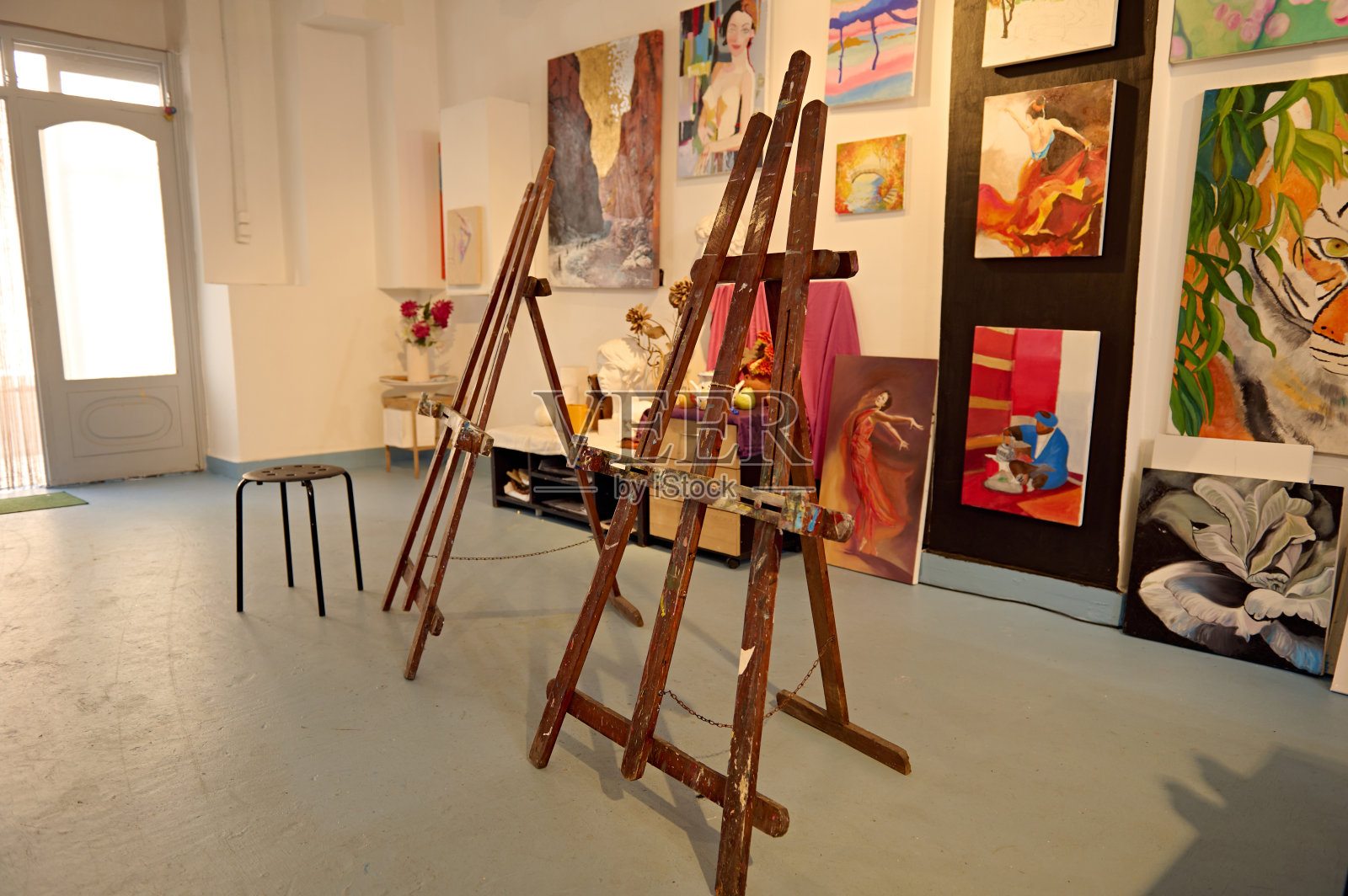 艺术工作室，白色的墙壁上陈列着画架和五颜六色的画作照片摄影图片