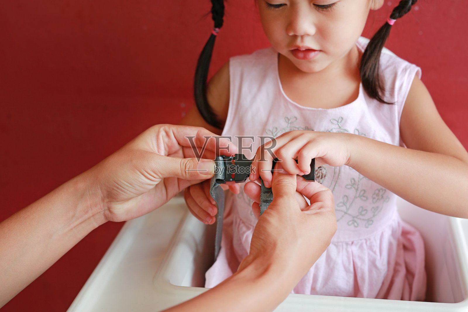 特写:孩子坐在高座椅上，系好安全带保护自己。照片摄影图片