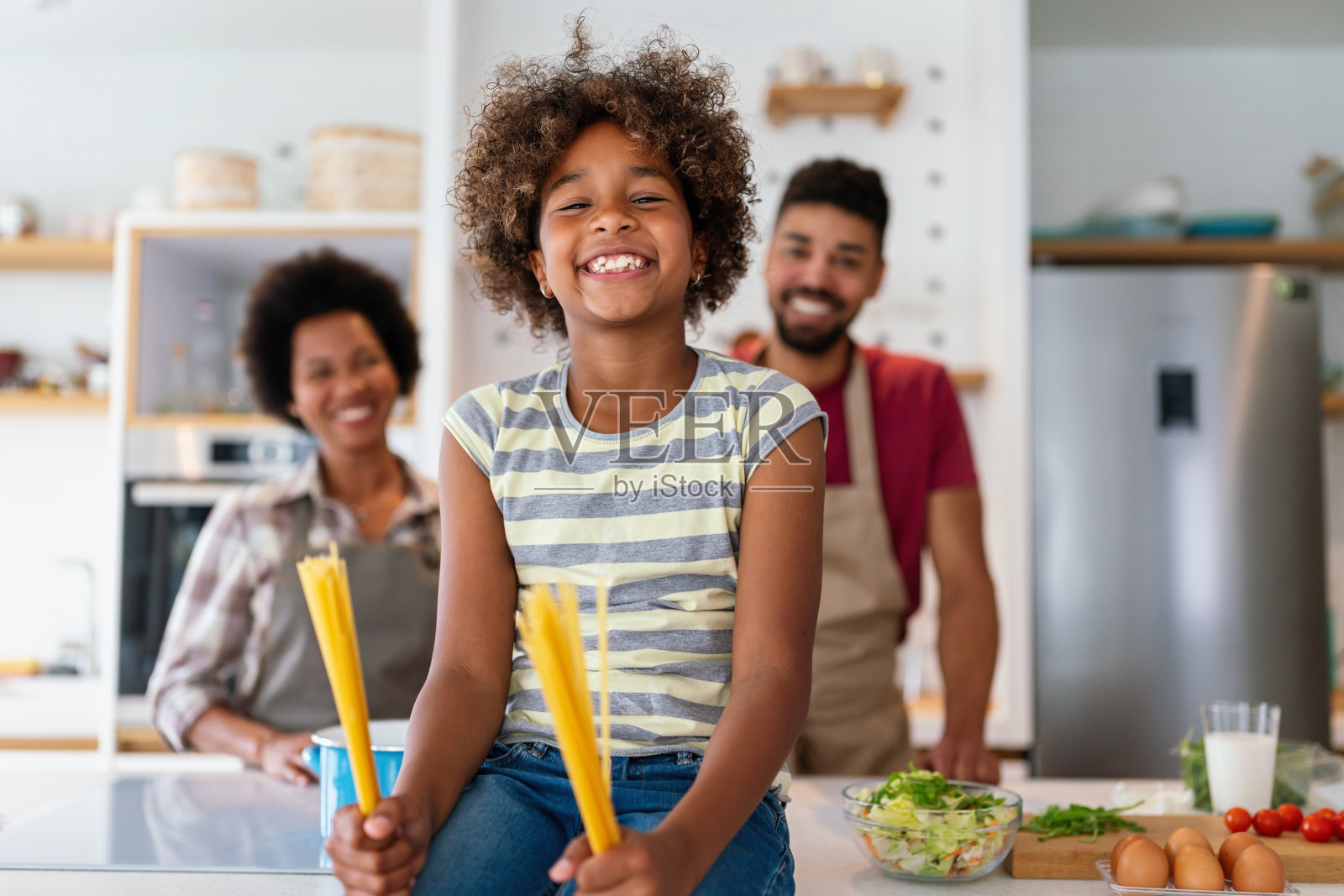 喜出望外的年轻非裔美国家庭和孩子一起在家里做饭，照片摄影图片