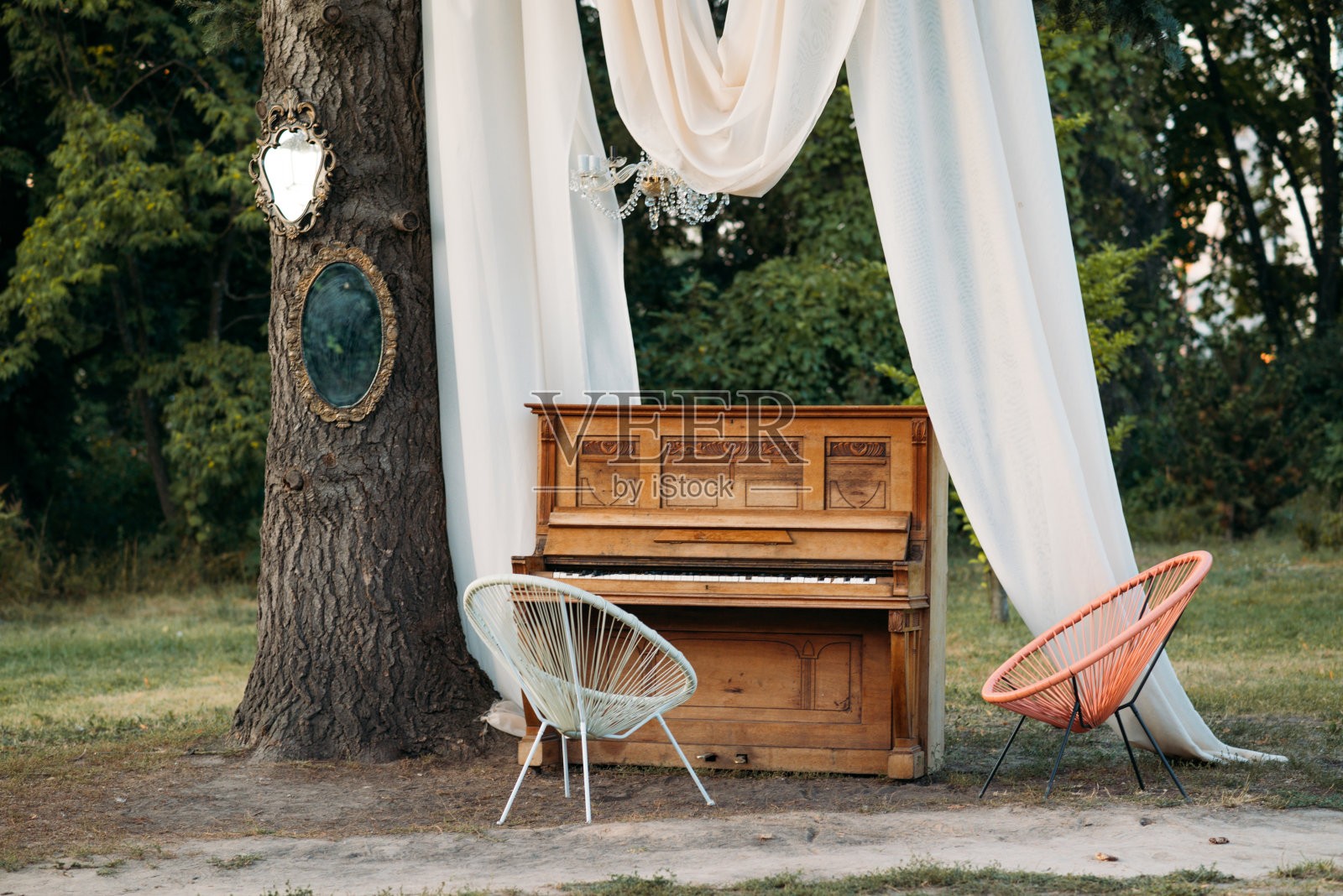 钢琴和椅子与浪漫的装饰在夏天的花园。婚礼或浪漫晚餐的装饰。照片摄影图片
