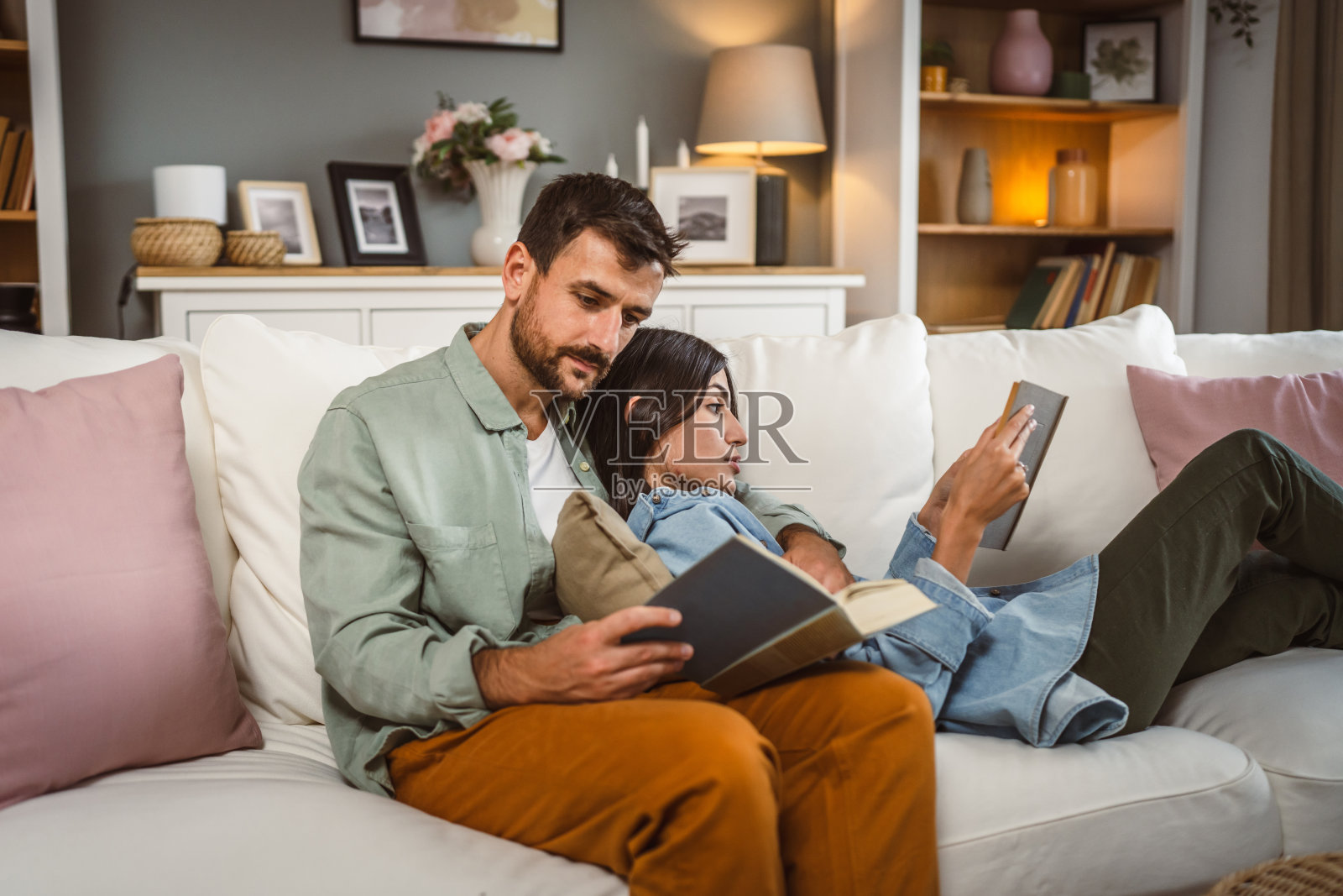 一男一女白种成年夫妇在家里沙发床上看书照片摄影图片