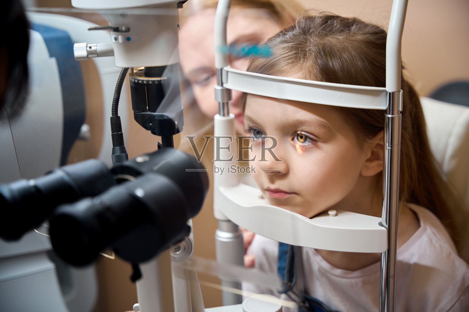 眼科医生用特殊的设备检查年轻病人的视力照片摄影图片