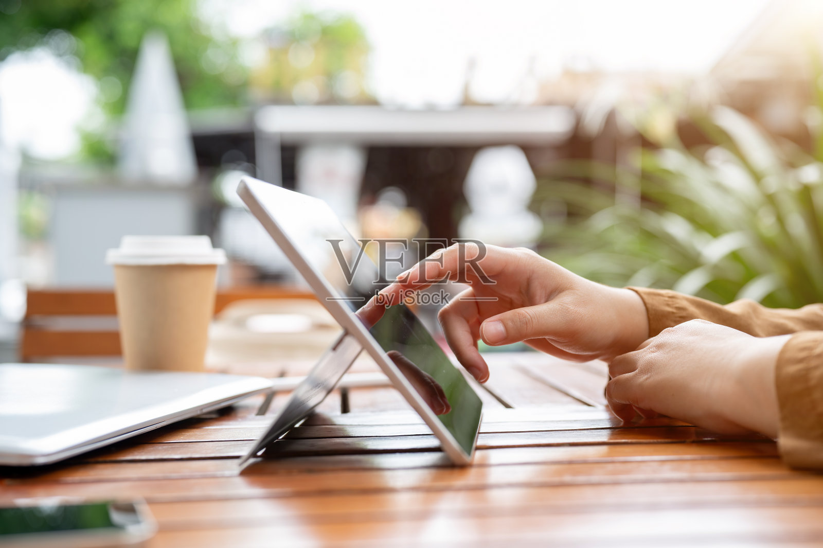 一个女人触摸着平板电脑屏幕的侧视图，在她的平板电脑上远程工作。照片摄影图片