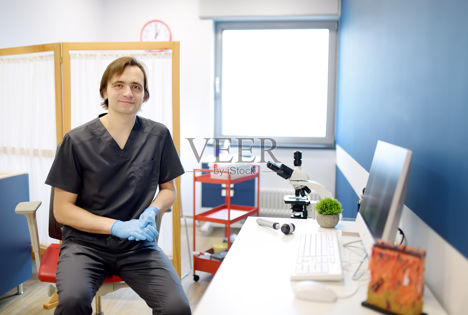 男性皮肤科医生在办公室在现代诊所的肖像。医生在工作地点预约病人。照片摄影图片