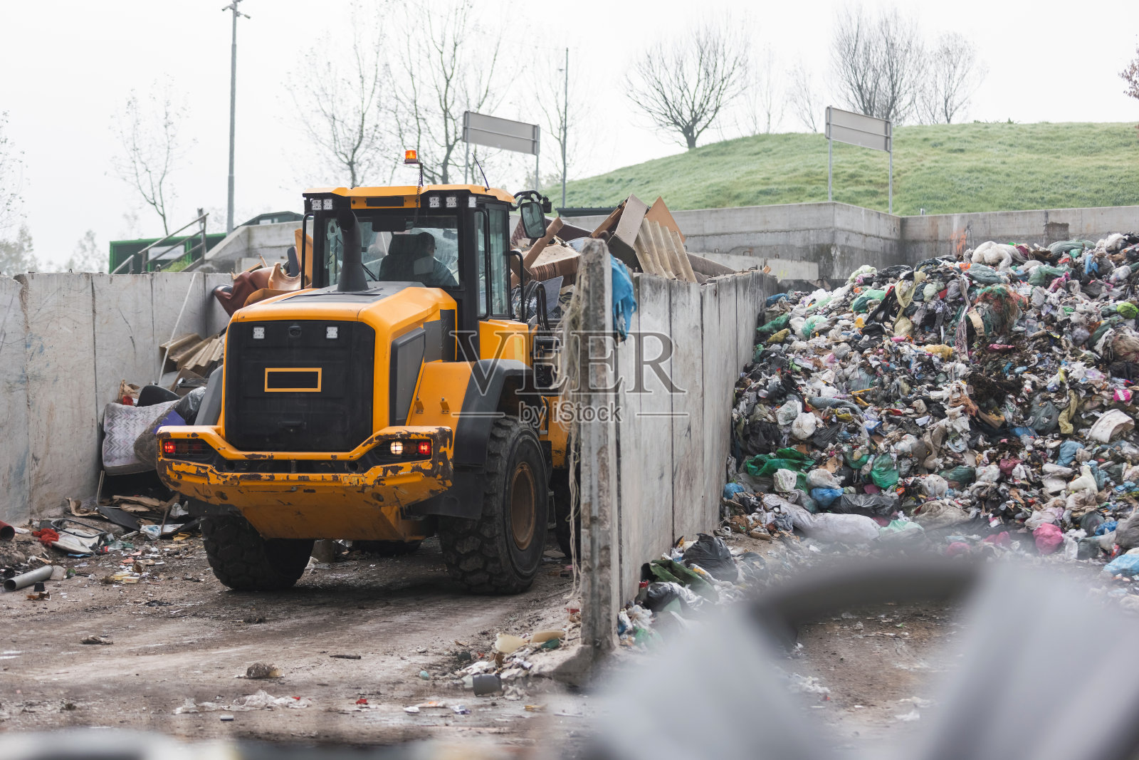 打滑式装载机在搬运废料，摇晃着一个废弃的抓斗照片摄影图片