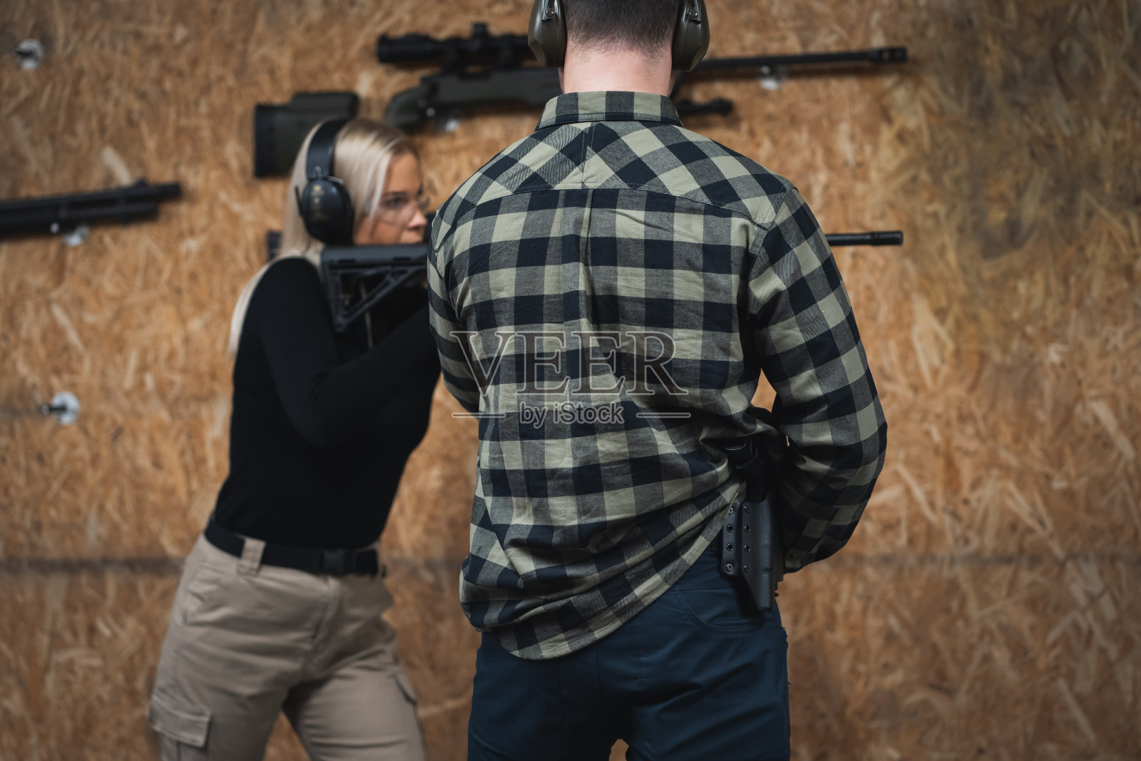 一个小女孩在射击场和教练一起学习射击战术步枪。照片摄影图片