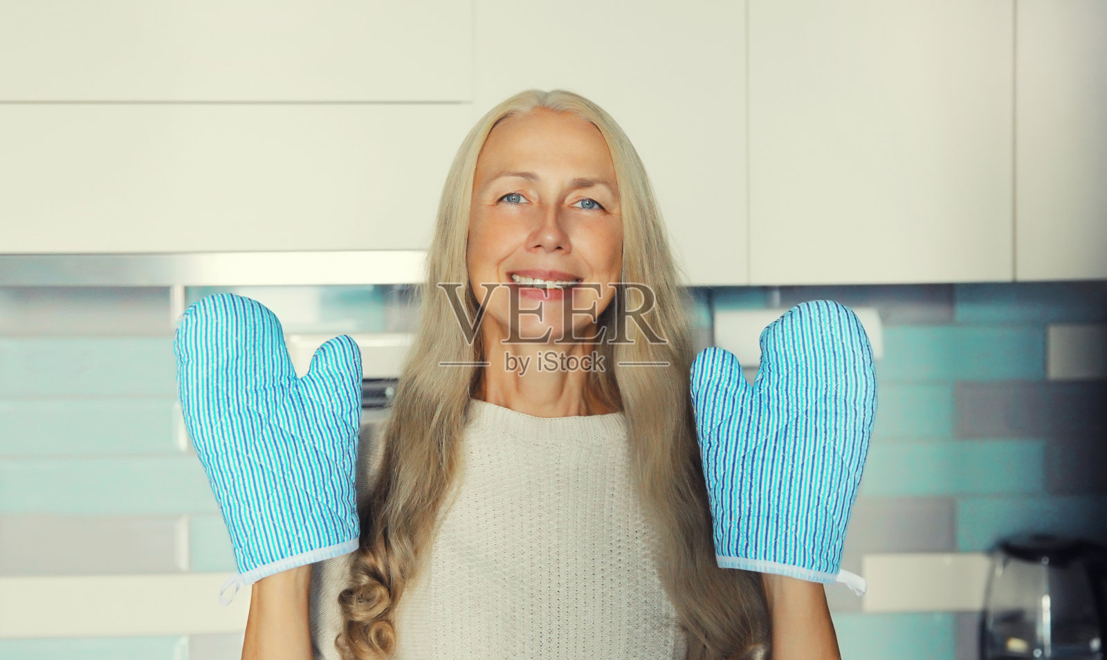 一个带着烤箱手套的家庭主妇正在厨房里忙着做饭照片摄影图片