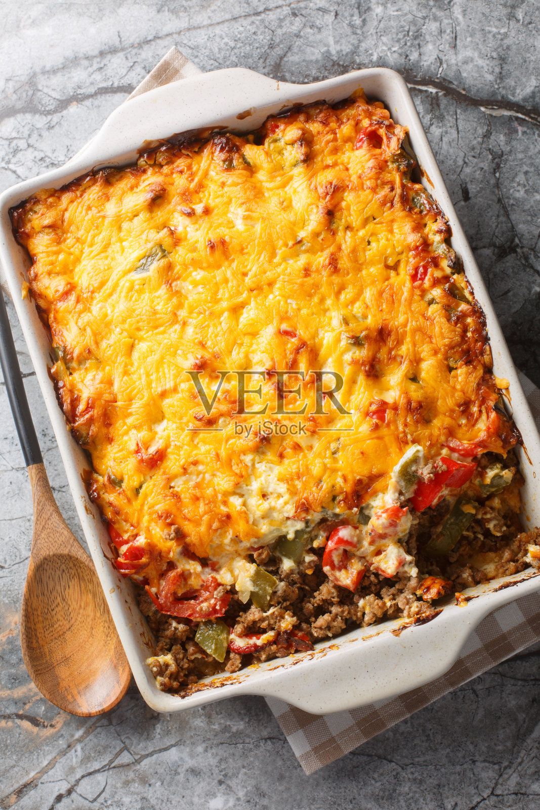 约翰·韦恩砂锅是用饼干面团和酸奶油、切达奶酪、西红柿和甜椒一起烹饪的墨西哥玉米卷牛肉。垂直俯视图照片摄影图片