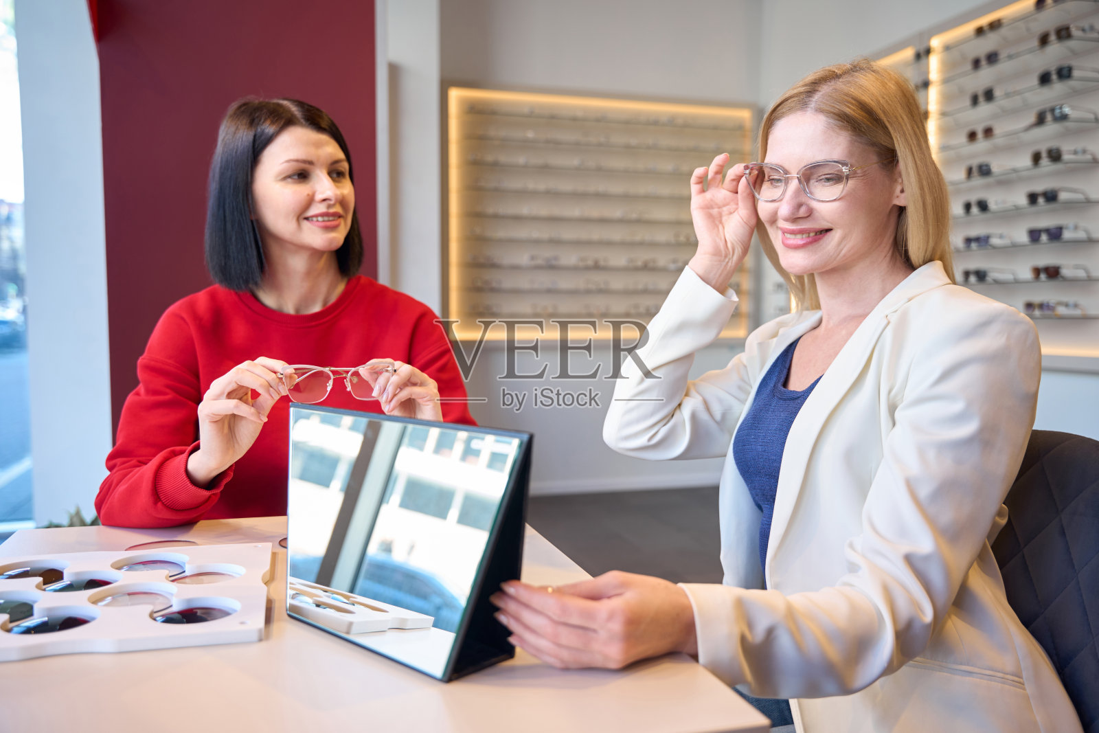 微笑的女人试着戴一副镜框时髦的眼镜照片摄影图片