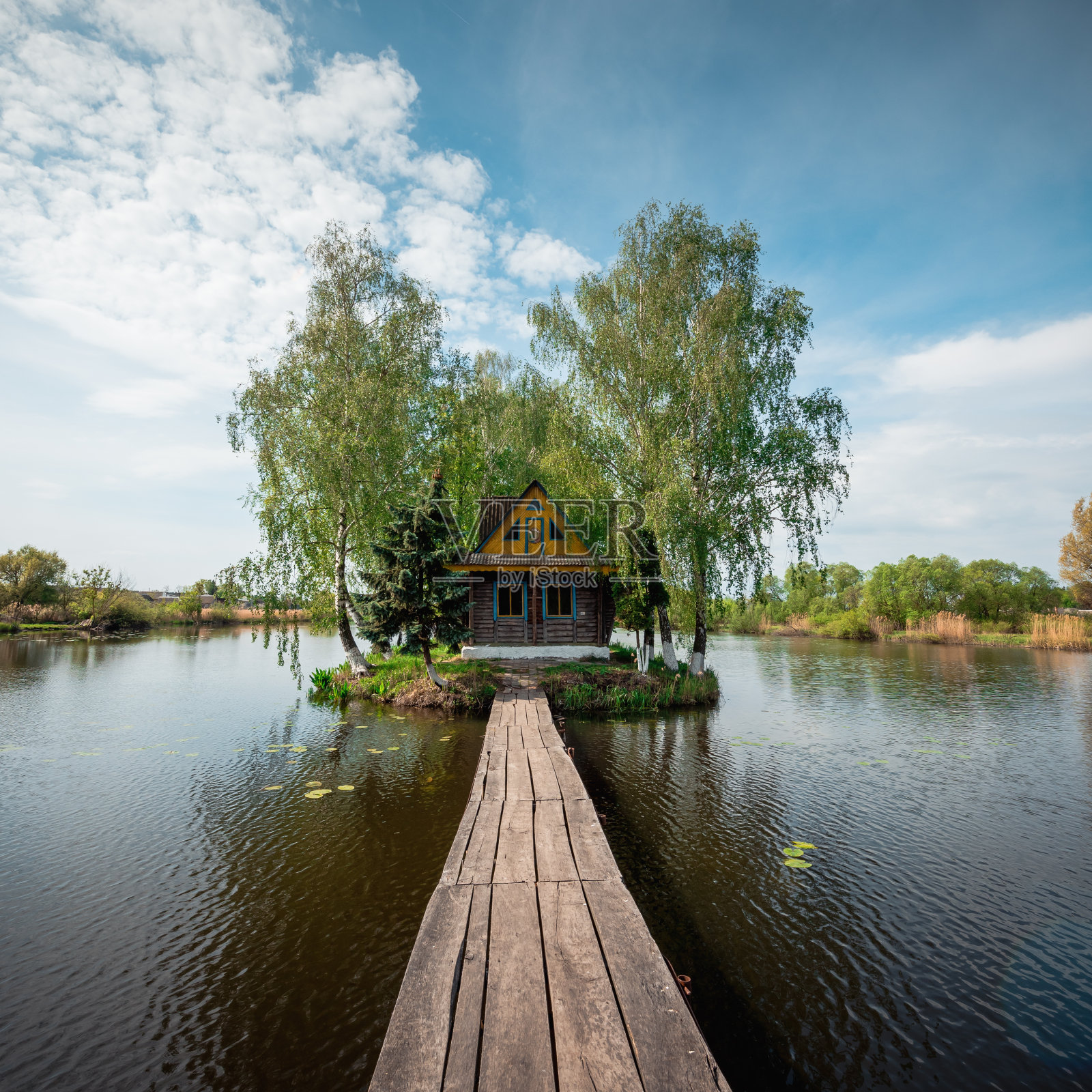 狭窄的木桥通往岛上的小房子。照片摄影图片