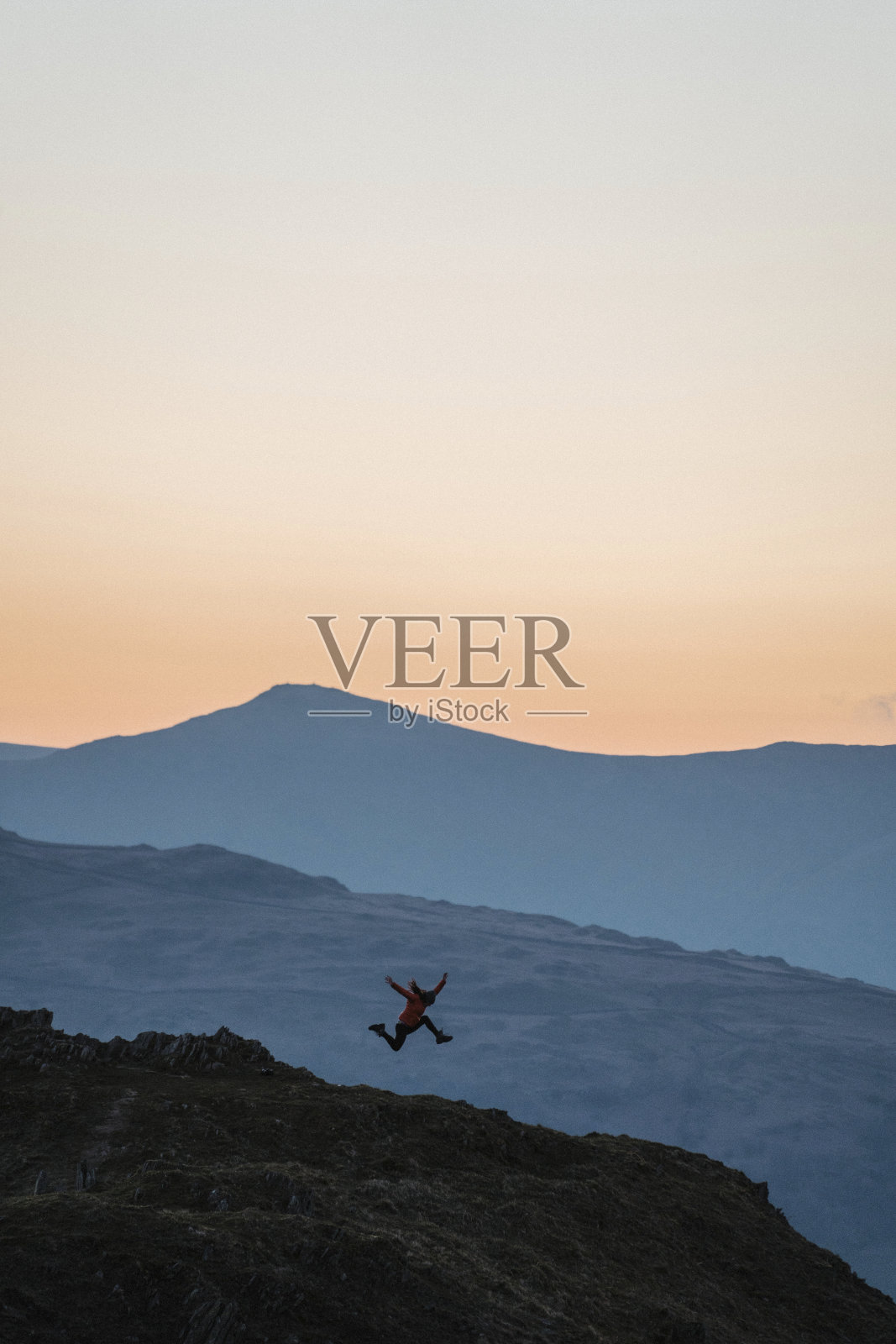 女子在英格兰湖区洛里格费尔山顶跳跃照片摄影图片