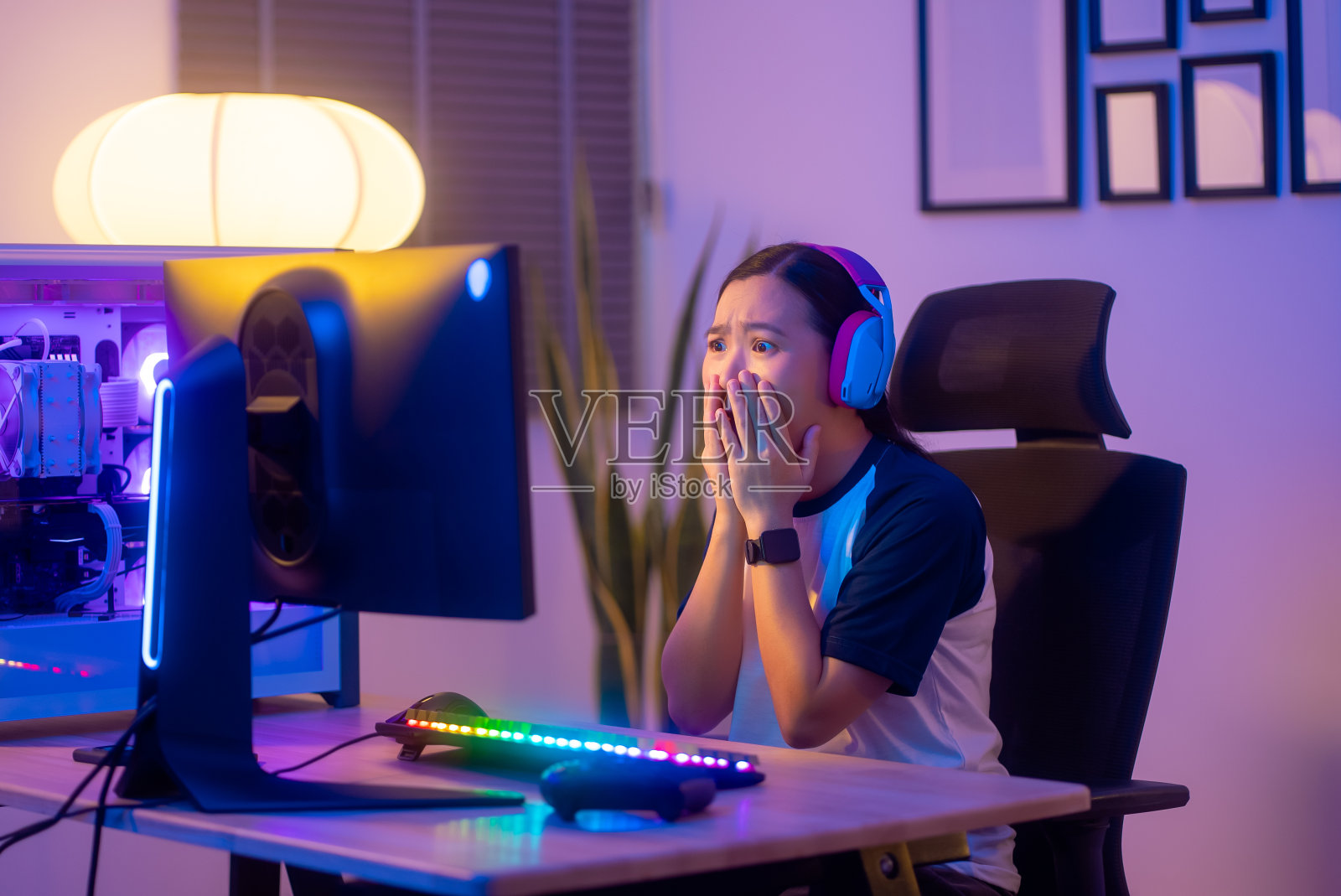 亚洲女玩家戴着耳机玩电脑游戏，在家里输了游戏后感到沮丧。照片摄影图片