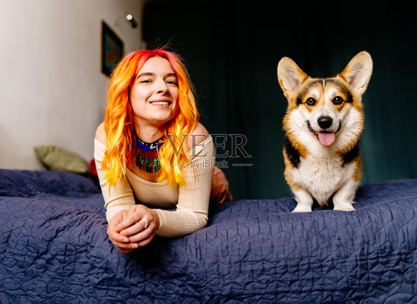 一个橙色头发的女人和一只狗躺在床上。女人在微笑，狗在摇尾巴照片摄影图片