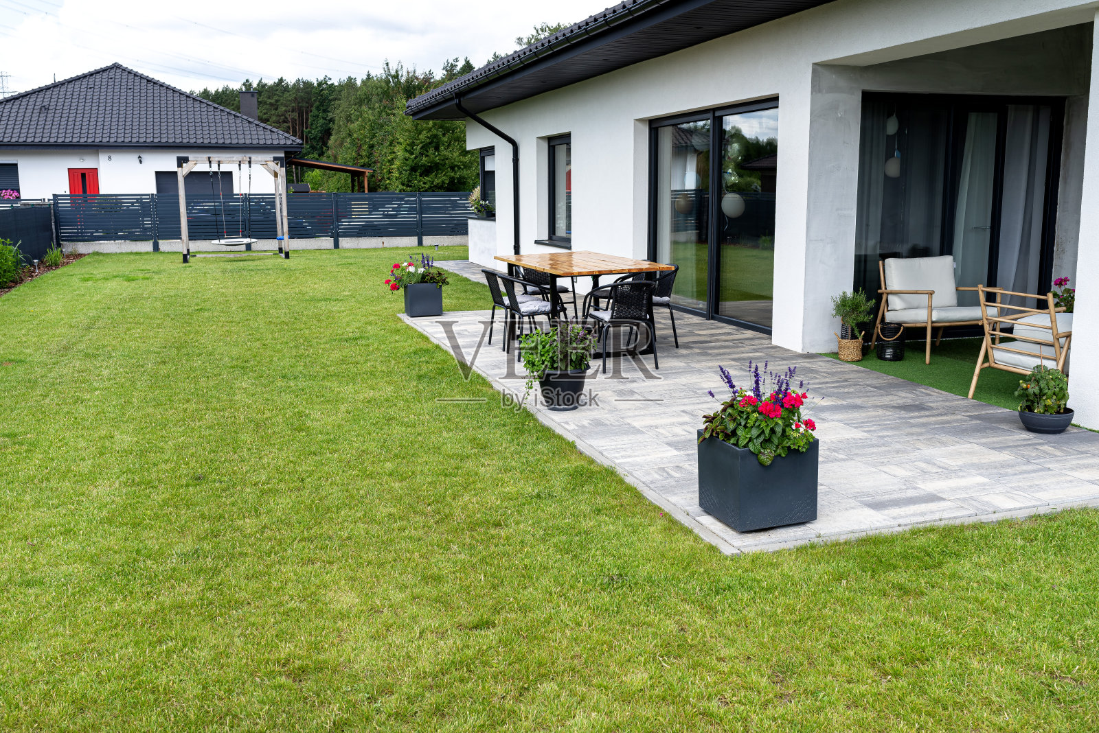 各种花草矗立在露台上的一个大花盆上，轮子上，草坪在背后。照片摄影图片