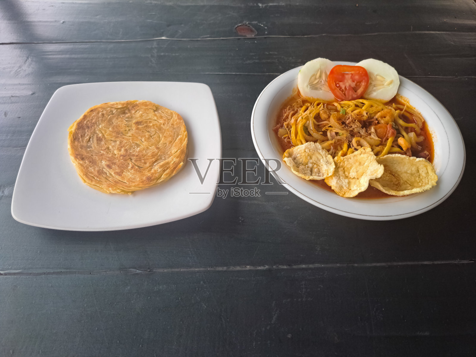 印度烤饼或帕拉塔面包。米亚齐海鲜或海鲜亚齐面条虾，蟹，鱿鱼，鱼，饼干，豆芽，葱，番茄和黄瓜。食品菜单。照片摄影图片