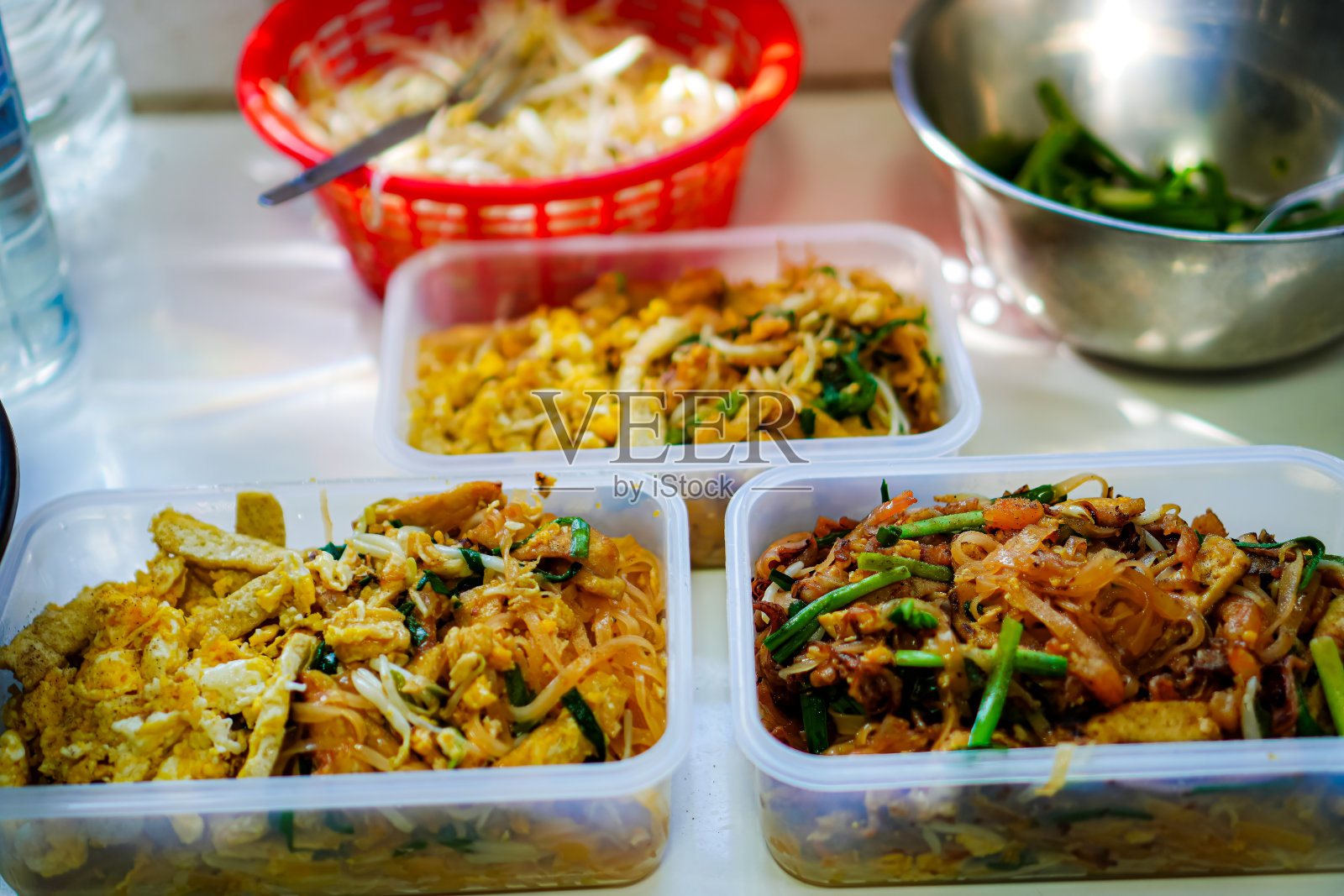 照片上的泰式炒面，新鲜的鱿鱼和对虾，包括素食泰式炒面，放在家里厨房的餐桌上。照片摄影图片