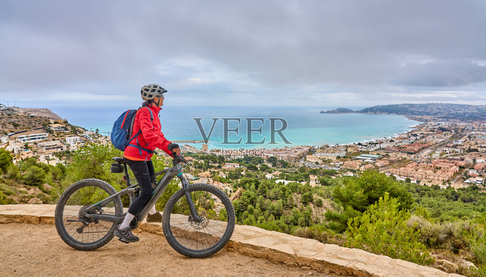 一名女子骑着电动登山车站在西班牙科斯塔布兰卡的悬崖上照片摄影图片
