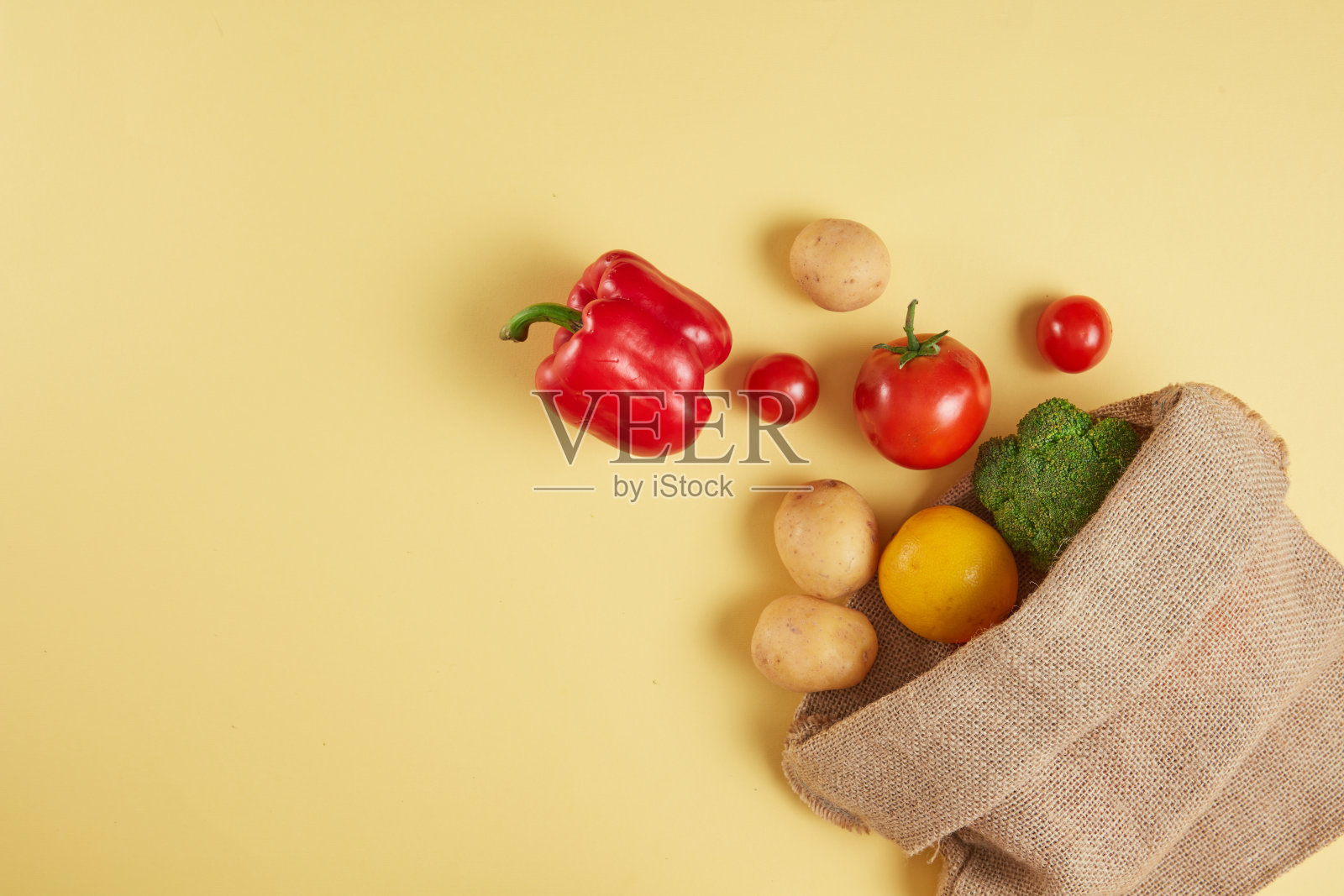 创意模板，在黄色背景上的新鲜蔬菜，用棕色帆布袋装饰。图片用于俯视图的宣传，左侧为产品展示留出空间照片摄影图片