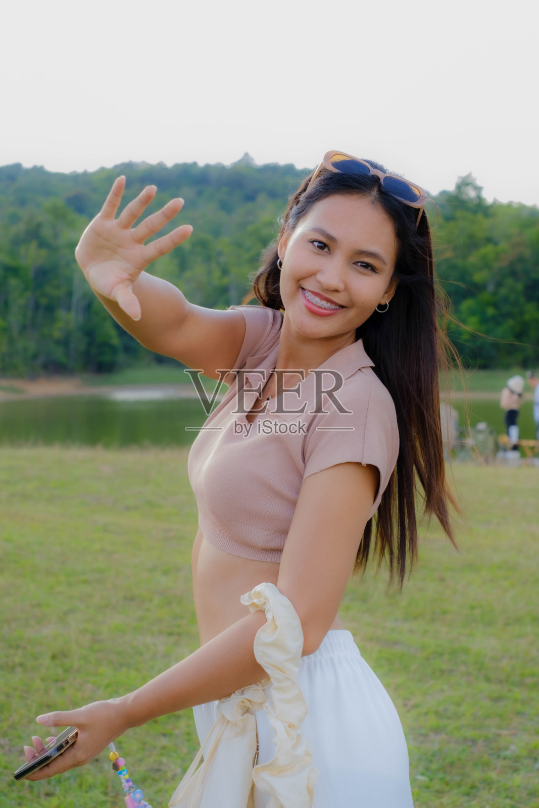 一个年轻的亚洲女人走在草地中间。照片摄影图片