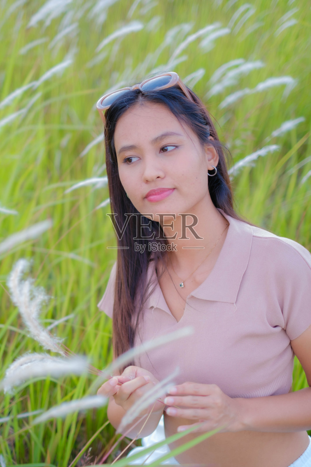 一个年轻的亚洲女人走在草地中间。照片摄影图片