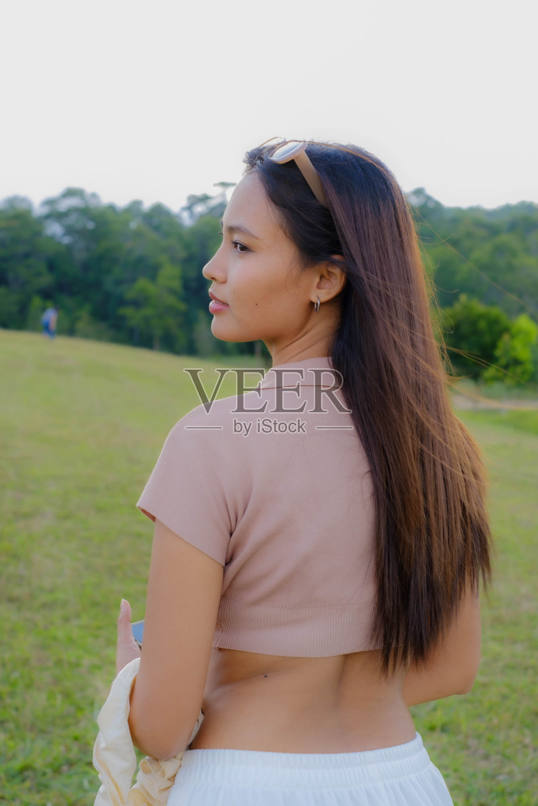 一个年轻的亚洲女人走在草地中间。照片摄影图片