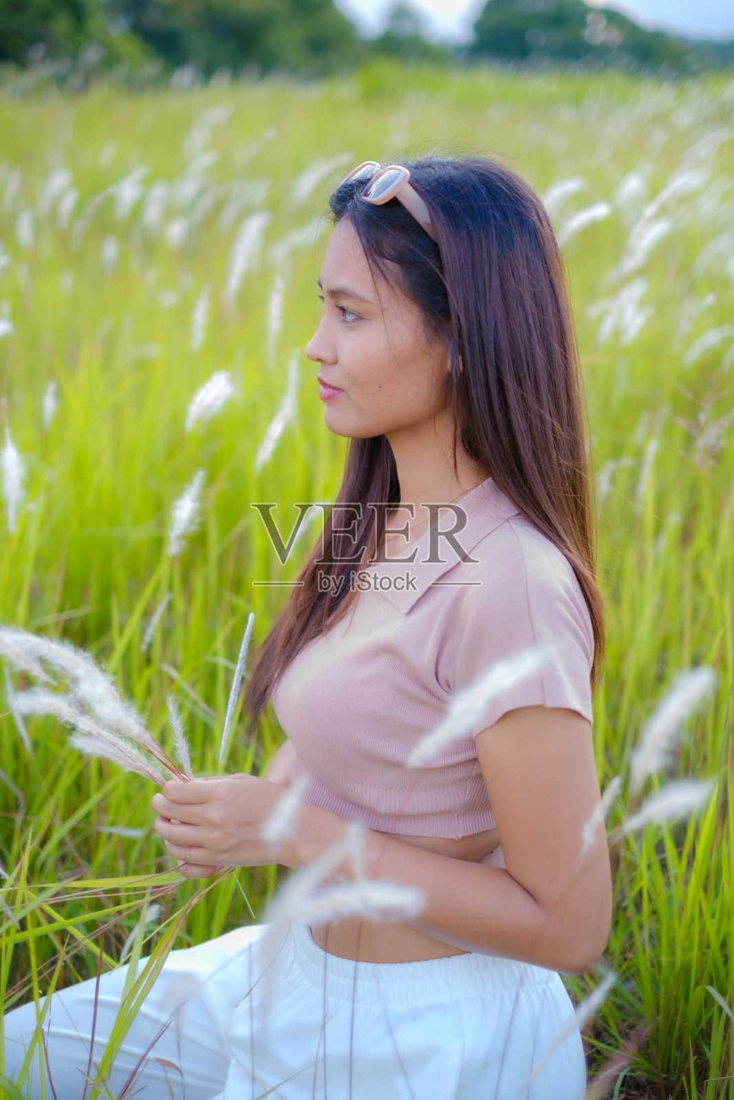 一个年轻的亚洲女人走在草地中间。照片摄影图片