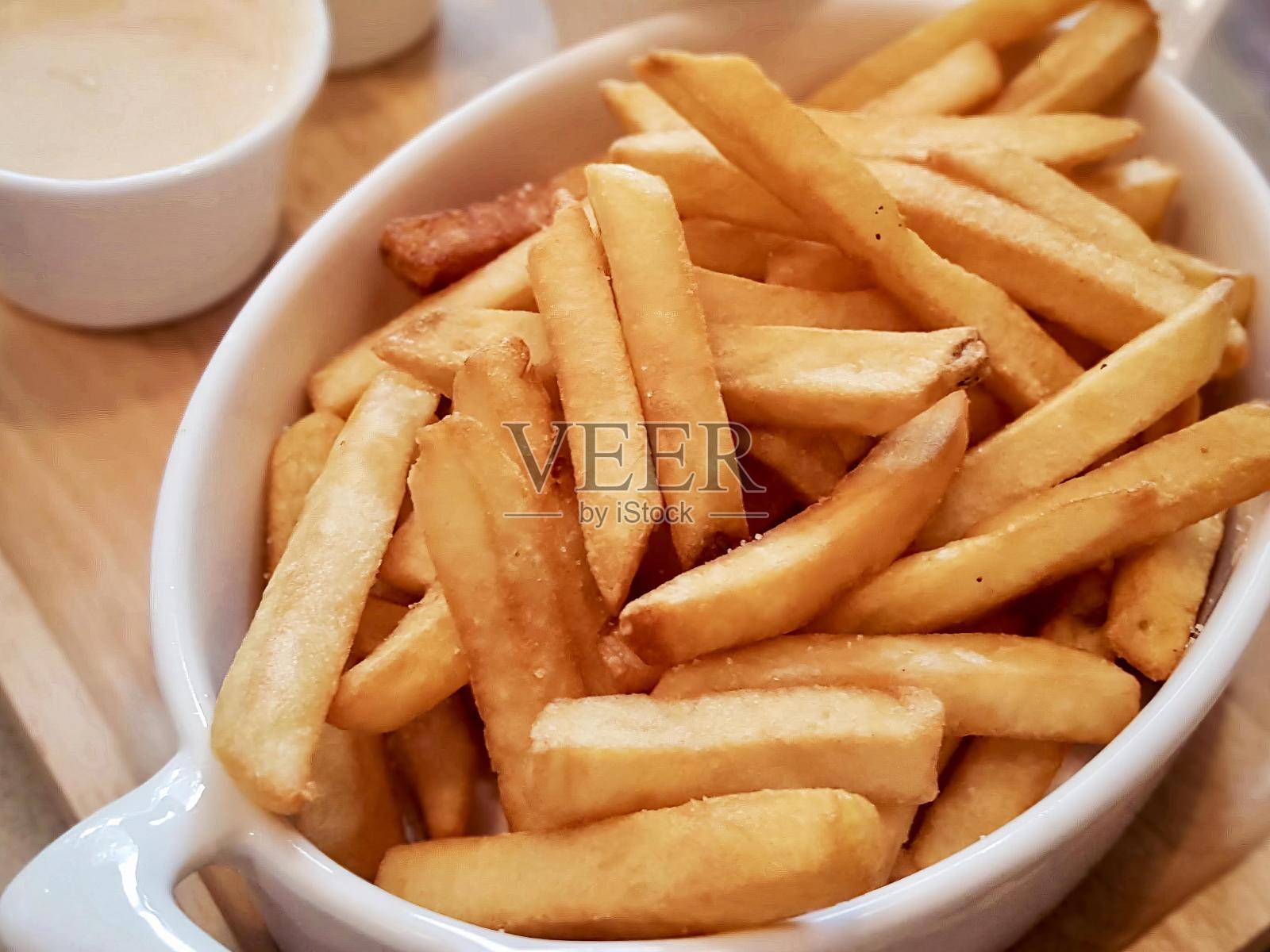 木托盘上一碗炸薯条的照片。照片摄影图片