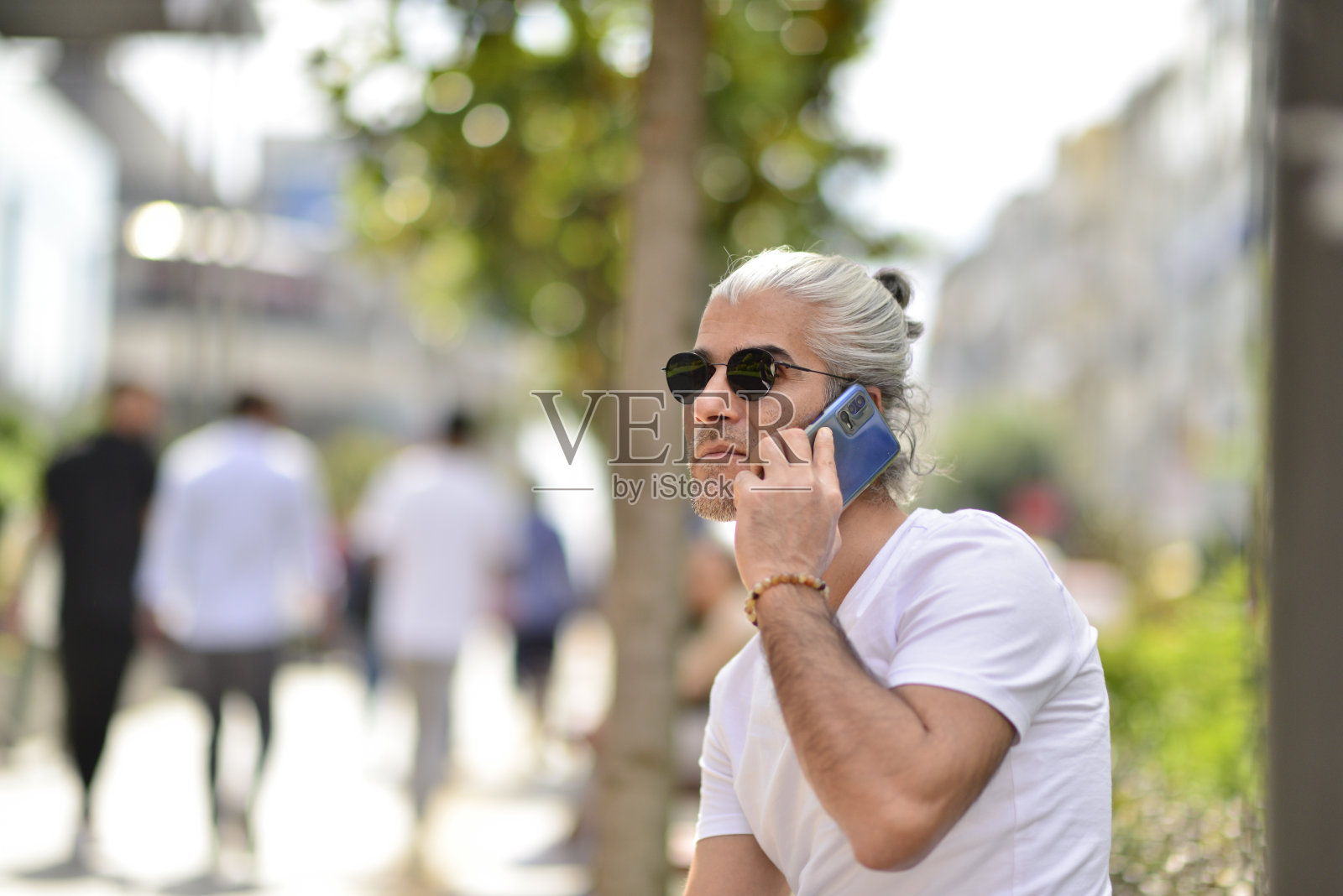 一个人坐在城市街道上的长凳上打电话照片摄影图片