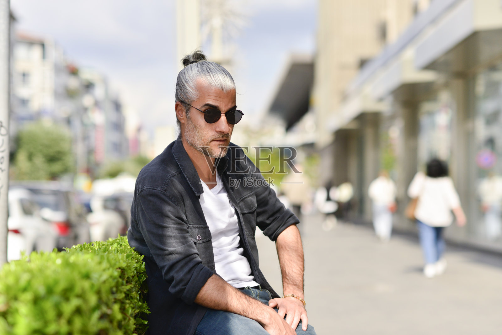 一个人坐在城市街道上的长凳上打电话照片摄影图片