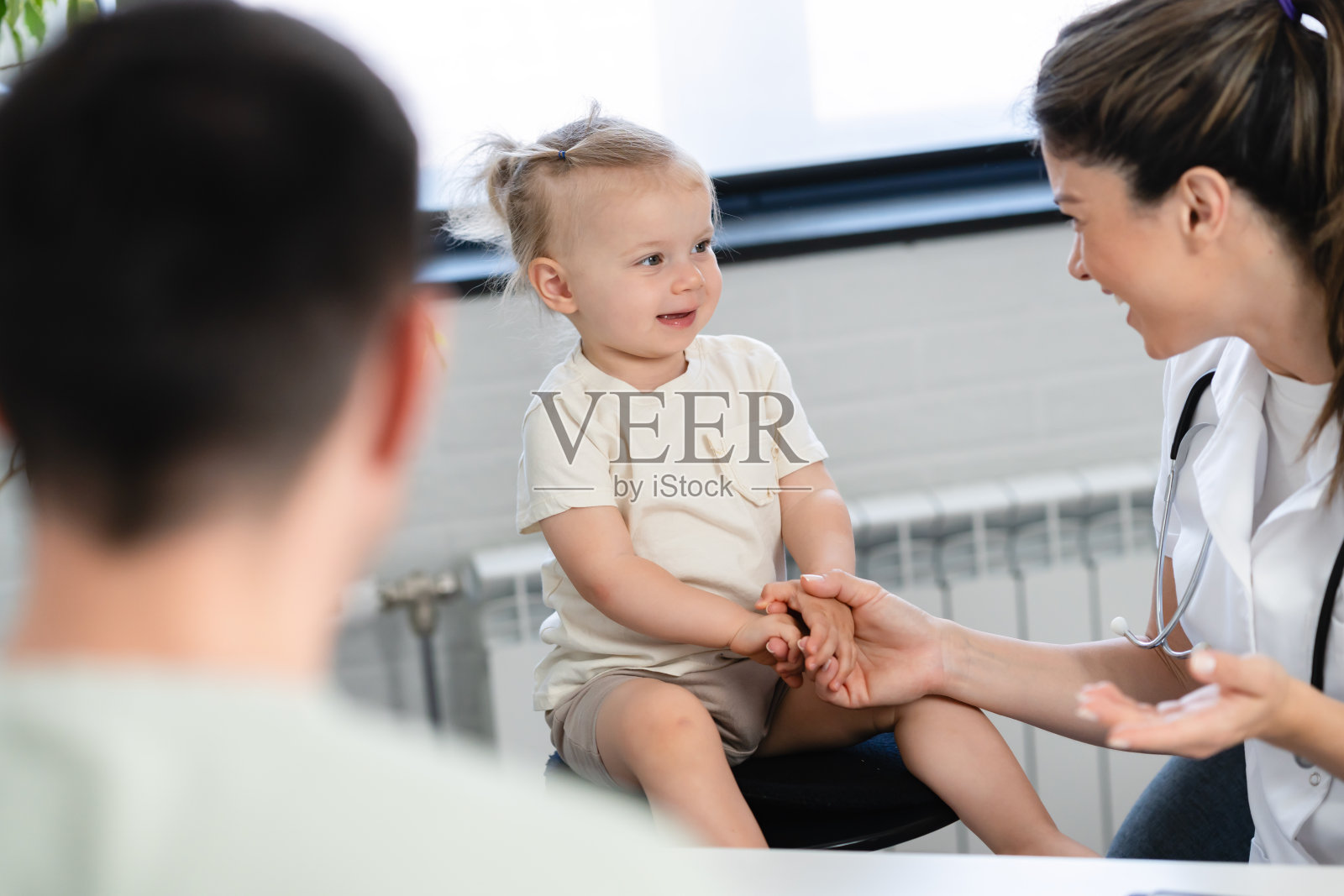 一位女儿科医生正在给她的小女孩病人做检查，并给她的父亲提建议照片摄影图片