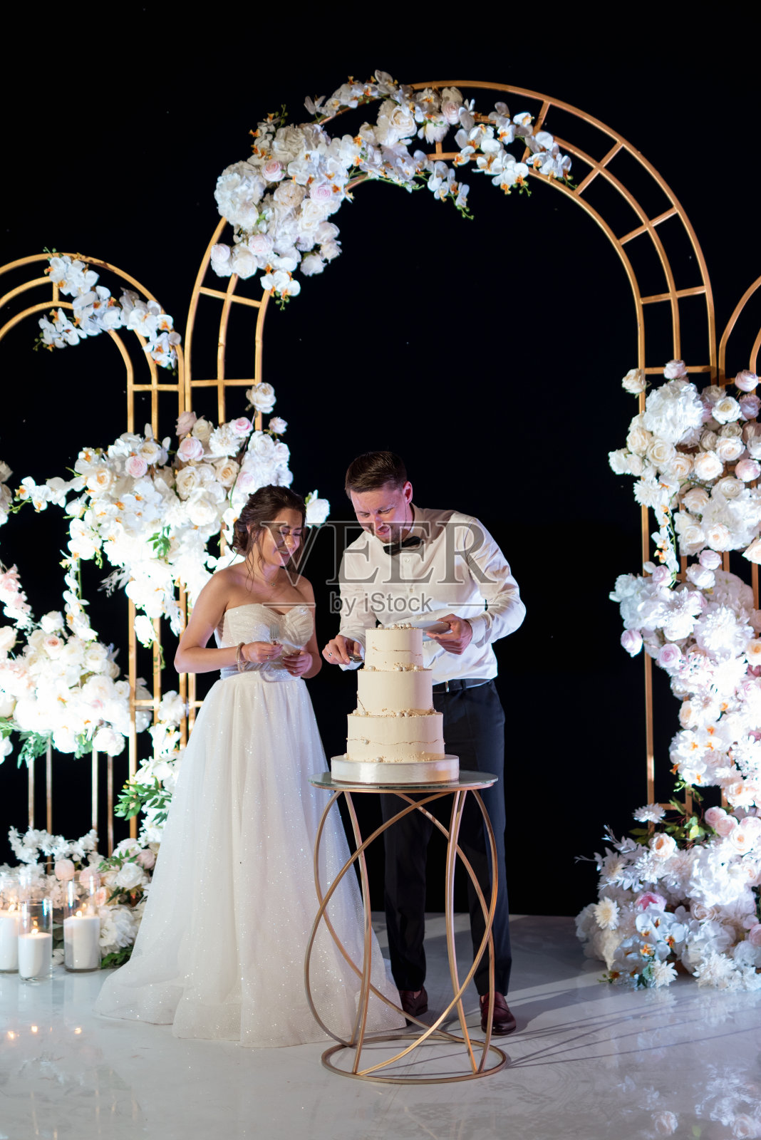 新婚夫妇幸福地切婚礼蛋糕并品尝照片摄影图片