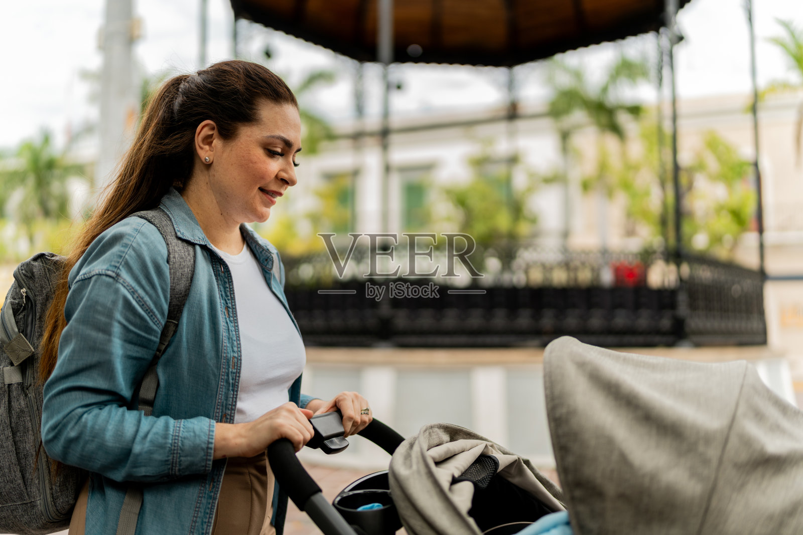 一位母亲推着婴儿车走在城市广场上照片摄影图片