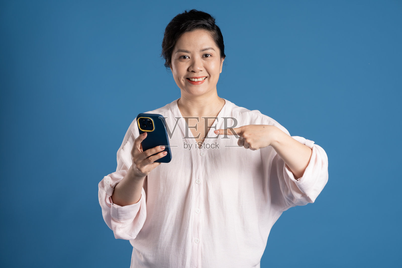 老亚洲妇女的肖像在蓝色背景上摆姿势照片摄影图片