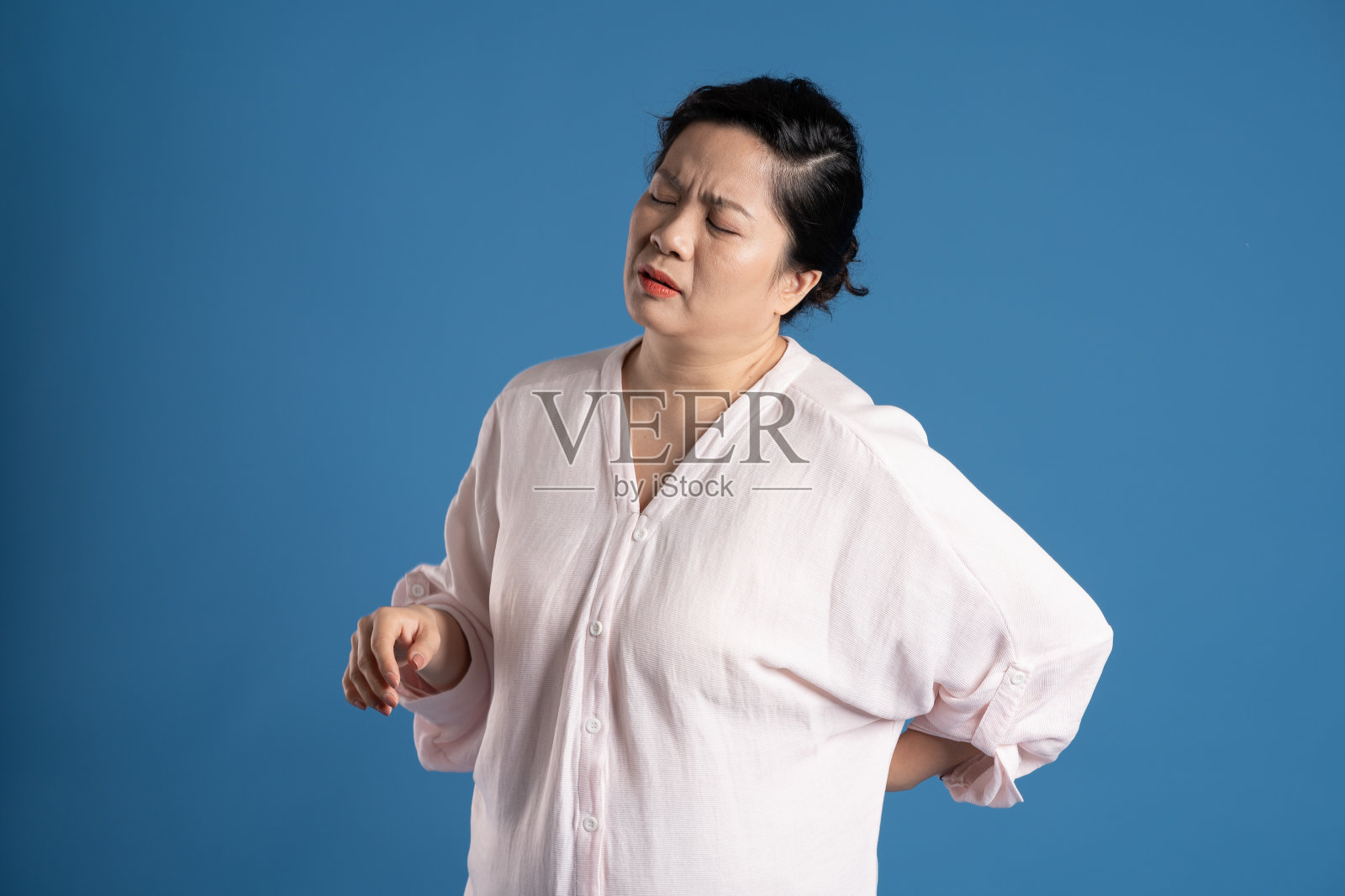 老亚洲妇女的肖像在蓝色背景上摆姿势照片摄影图片