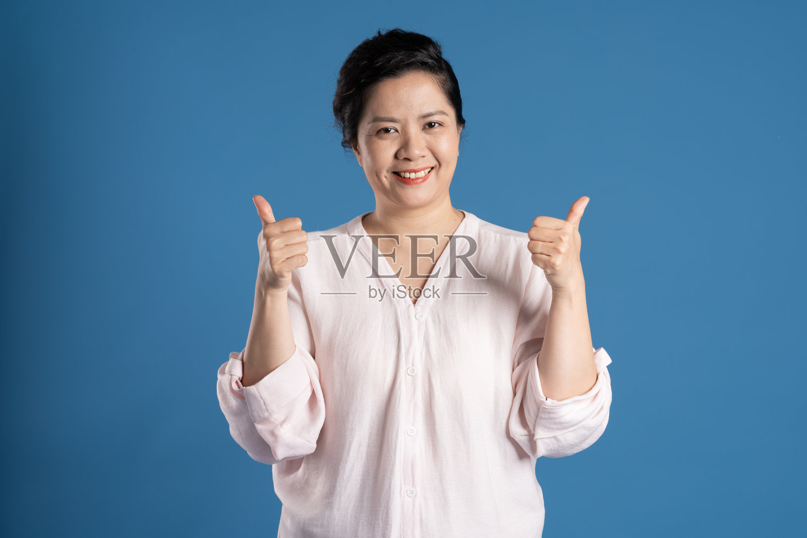 老亚洲妇女的肖像在蓝色背景上摆姿势照片摄影图片