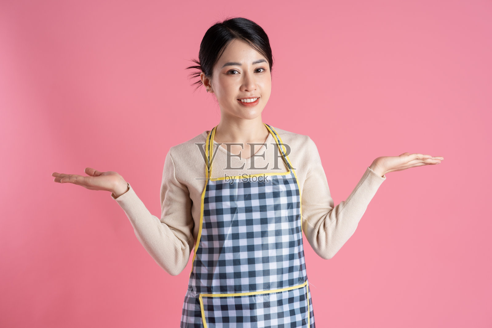 穿着围裙的女人的肖像，在粉红色的背景上摆姿势照片摄影图片