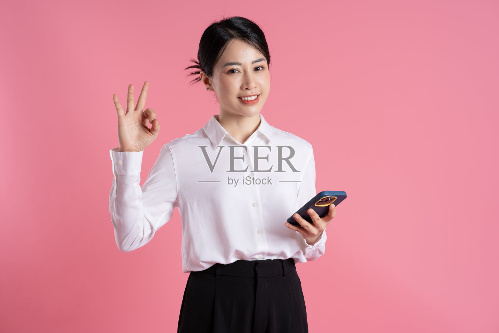 美丽的亚洲女商人在粉红色背景上摆姿势的肖像照片摄影图片